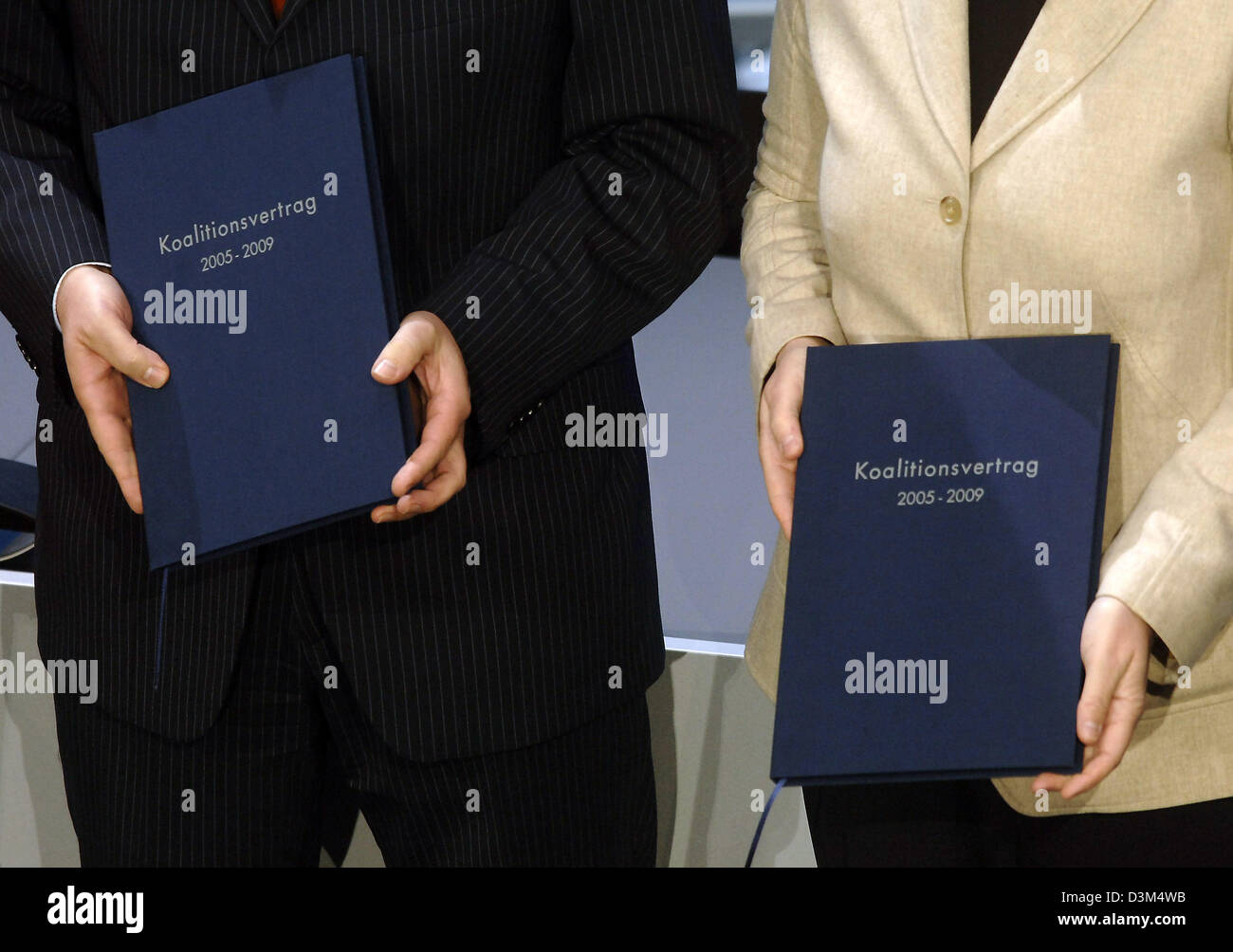 (dpa) - Matthias Platzeck (L), Chairman of the Social Democrats (SPD) and Angela Merkel, Chairwomen of the conservative Christian Democrats (CDU) and designated German Chancellor hold both a copy of the coalition agreement in their hands in Berlin, Friday, 18 November 2005.Merkel is expected to be elected as Germany's first female chancellor in the parliamentary session of the Bund Stock Photo