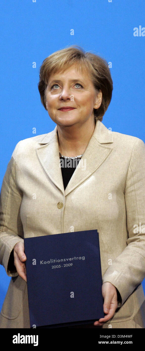 (dpa) - Angela Merkel, Chairwomen of the conservative Christian Democrats (CDU) and designated German Chancellor, holds a copy of the coalition agreement in her hands in Berlin, Friday, 18 November 2005. Merkel is expected to be elected as Germany's first female chancellor in the parliamentary session of the Bundestag on Tuesday, 22 November 2005. Photo: Peer Grimm Stock Photo