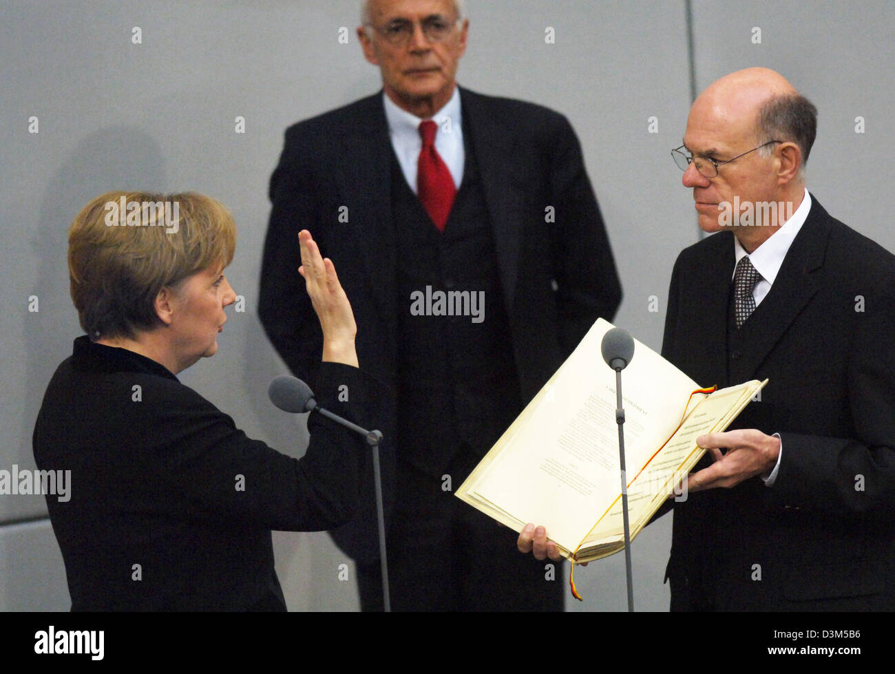 (dpa) - New elect German Chancellor Angela Merkel (L) takes the oath of office to President of the Bundestag, Norbert Lammert (R), as Wolfgang Zeh, director of the Bundestag looks on in Berlin, Germany, Tuesday 22 November 2005. Merkel of the conservative Christian Democratic Union (CDU) was elected with the majority votes of the parliament confirming her as the first female chance Stock Photo
