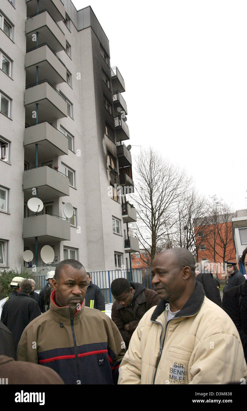 (dpa) - Men stand in front of a seven-storey dwelling house with a soot-stained facade in Cologne-Muelheim, Germany, 24 December 2005. Five people, including two small brothers, were killed in a fire in this house early 24 December. Six others were injured in the fire. Four of the killed people belong to an extended family from Angola, according to police. The cause of the pre-holi Stock Photo