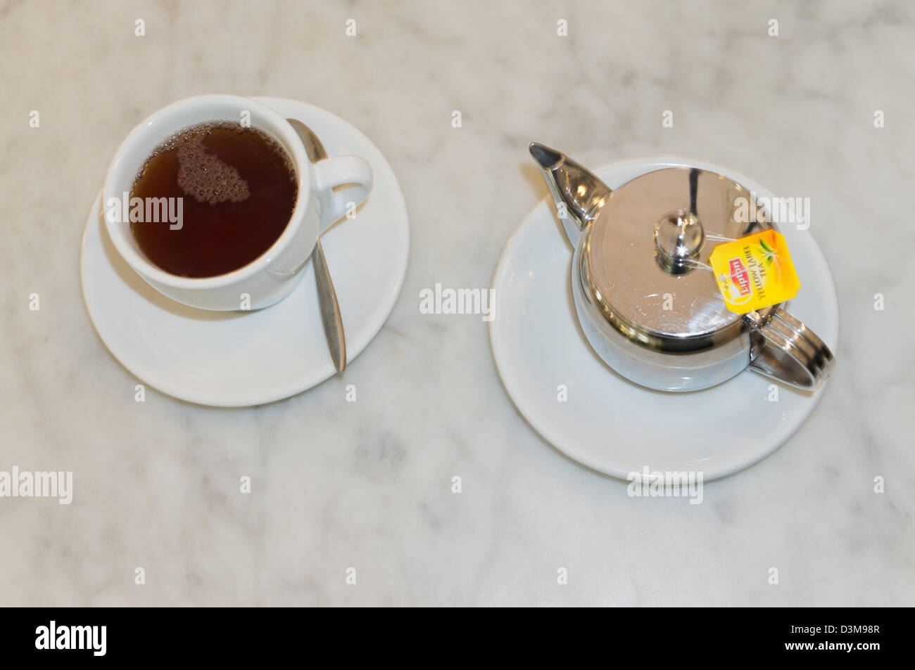 Cup of Liptons tea and stainless steel teapot on marble surface Stock Photo