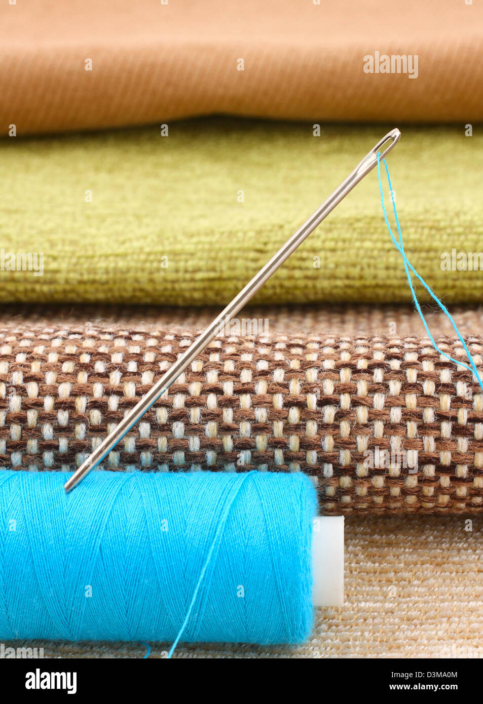 spool of thread with needle on fabric background Stock Photo