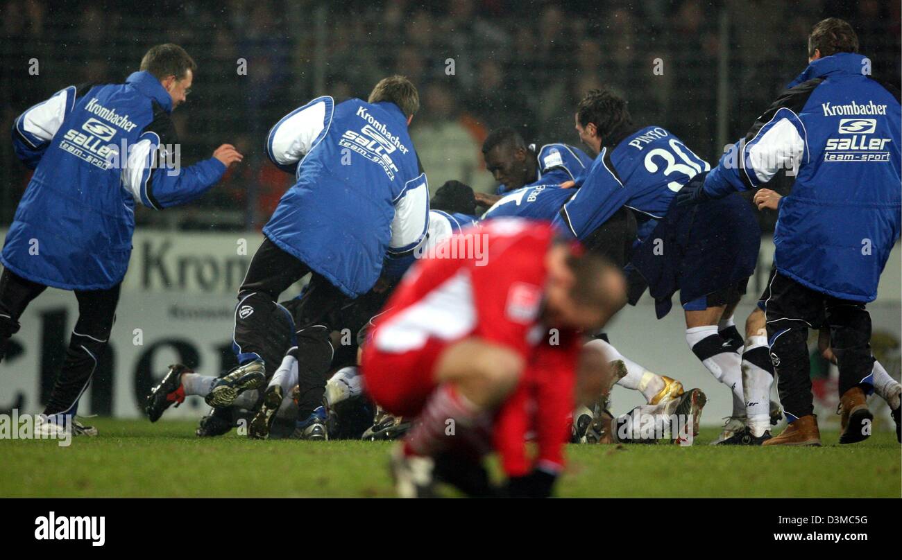 Kickers Offenbach's Stephan Sieger (front) moans about his team's defeat at the German Cup quarter-finals soccer match against Arminia Bielefeld at the Schueco Arena stadium in Bielefeld, Germany, Wednesday 25 January 2006. Sieger failed to score from the penalty spot. In the background cheer players of Bielefeld. Around12,000 spectators watched Bielefeld advance to the semi-finals Stock Photo