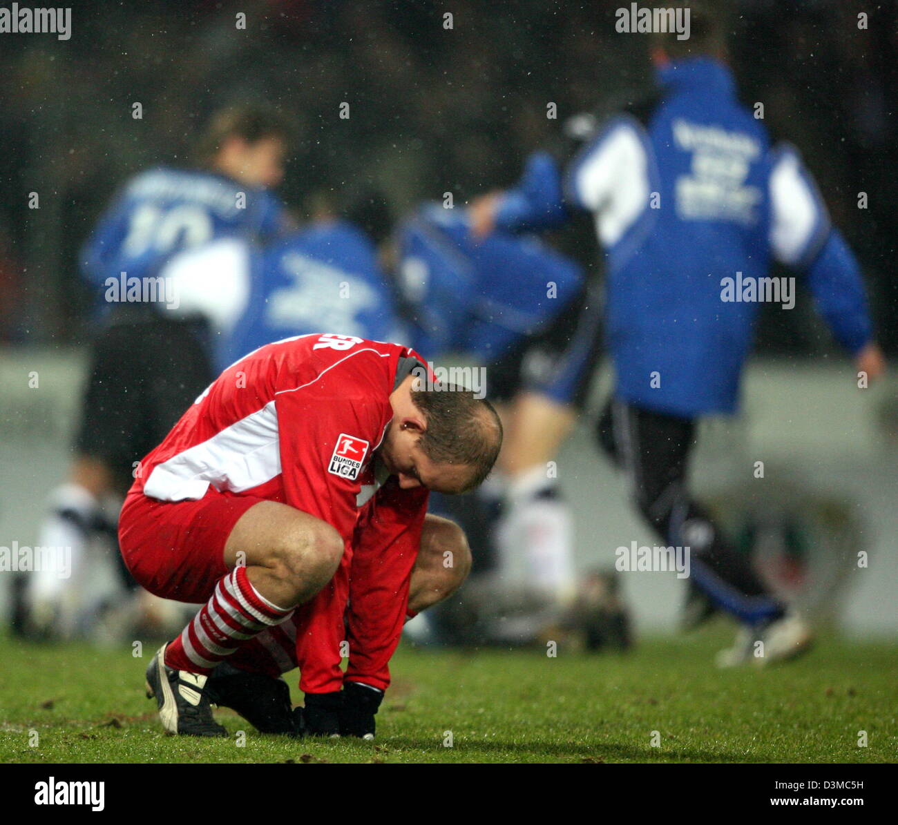 Kickers Offenbach's Stephan Sieger (front) moans about his team's defeat at the German Cup quarter-finals soccer match against Arminia Bielefeld at the Schueco Arena stadium in Bielefeld, Germany, Wednesday 25 January 2006. Sieger failed to score from the penalty spot. In the background cheer players of Bielefeld. Around 12,000 spectators watched Bielefeld advance to the semi-final Stock Photo