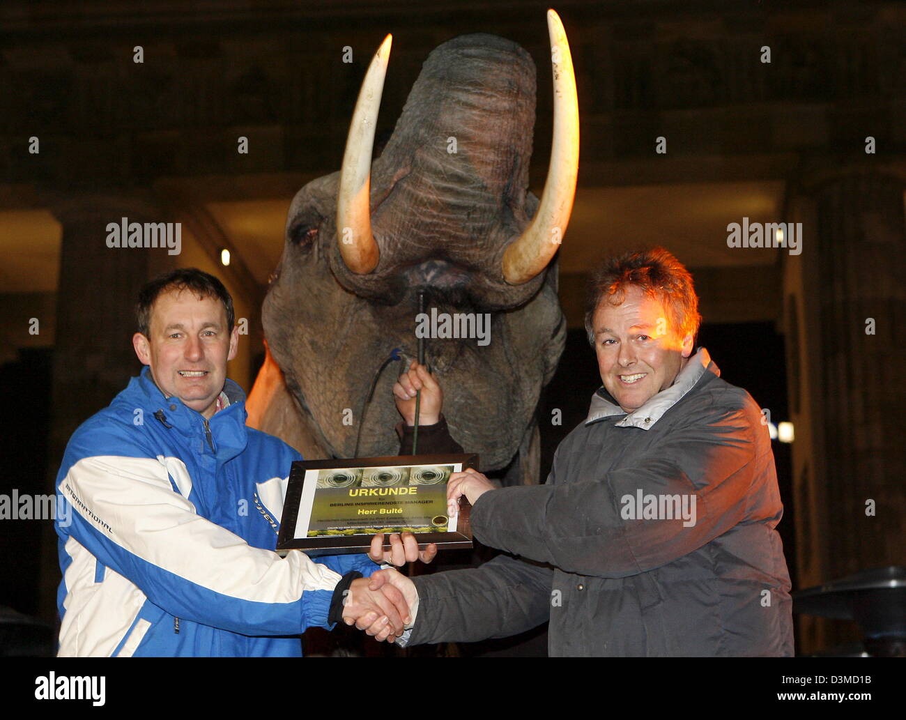 Dutch authors Salem Smhoud (L) and Hans van der Loo award each other a certificate, while elephant Marla is watching their backs in front of Brandenburger Gate in Berlin, Germany, Thursday 02 February 2006. The authors have written the book 'Lust und Leistung' (joy and performance) about business managers in which they call them 'Memofanten' (short for memory elephants). Since no B Stock Photo