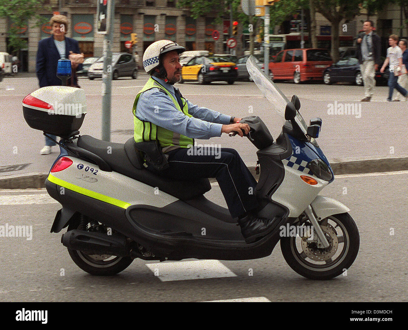 (dpa file) - A traffic police officer of the Guardia Urbana (city traffic police) drives on his scooter through downtown Barcelona near the Arc de Triomf square, Spain, 10 June 2002. Because of their blue uniform they are often mistaken as Policia Nacional officers (national police), who are however responsible for national security matters. Only the blue and white chequered strips Stock Photo