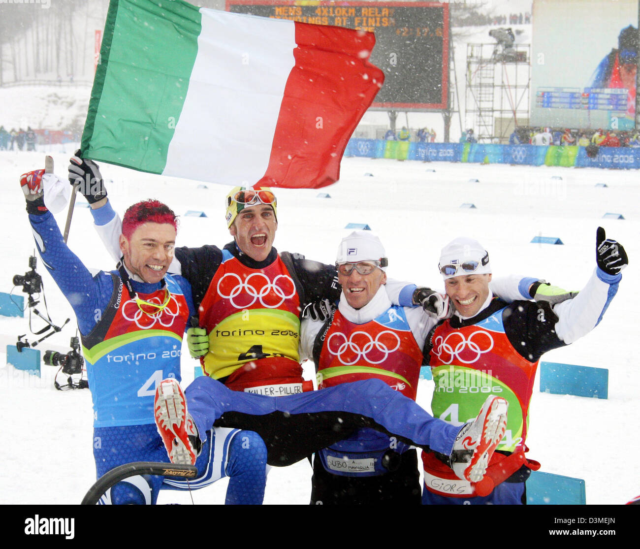 The Italian relay runners Christian Zorzi, Pietro Piller Cottrer, Fulvio Valbusa and Giorgio di Centa celebrate with the Italian flag their victory in the men's 4x10 kilometres cross-country relay competition of the XX Olympic Winter Games, Pragelato Plan near Turin, Italy, Sunday 19 February 2006. Italy won the gold medal ahead of runner-up Germany and Sweden.The XX Olympic Winter Stock Photo