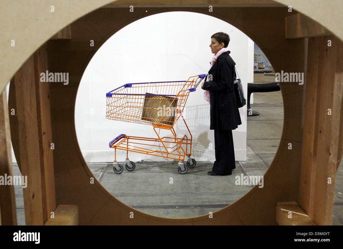 A visitor inspects the supermarket trolley of artist Philip Wiegard at the 'fine art fair frankfurt' in Frankfurt Main, Germany, Wednesday, 15 March 2006. Almost 50 galleries exhibit modern art from mainly young artists at the offspring fair of the former 'Art Frankfurt'. Photo: Frank Rumpenhorst Stock Photo