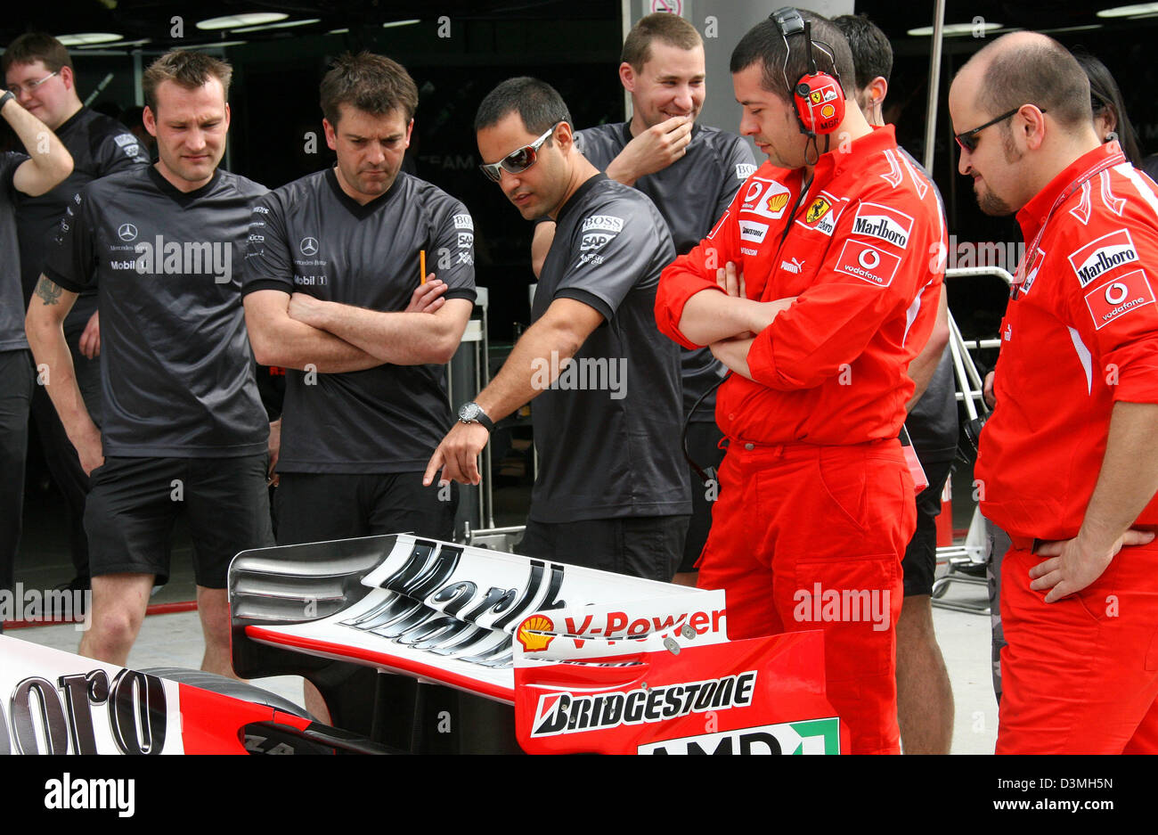 Colombian Formula One Driver Juan Pablo Montoya (C, with sun glasses) of Mercedes-McLaren F1 team examines the Ferrari of Michael Schumacher during the first practice session at the racetrack in Sepang near Kuala Lumpur, Malaysia, Friday 17 March 2006. The Grand Prix of Malaysia takes place on Sunday 19 March 2006. Photo: Jens Buettner Stock Photo