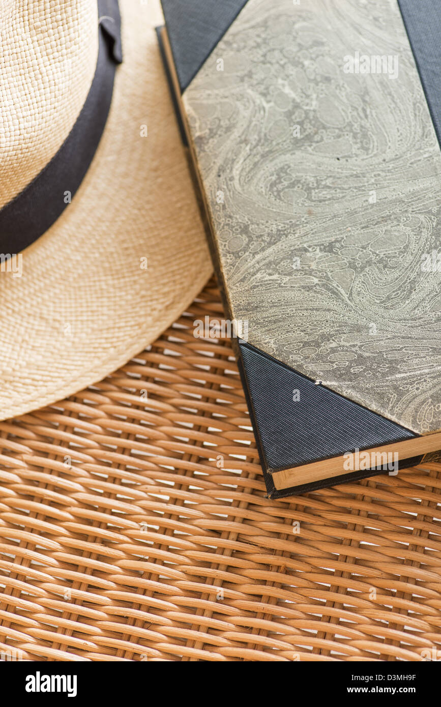 Vintage book and classic straw hat lying on wicker chair Stock Photo