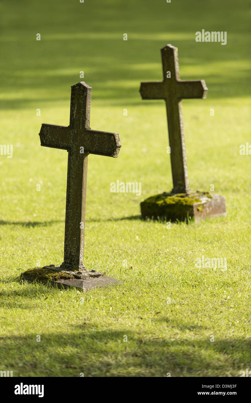 Two old graves with christian crosses on green grass of cemetery Stock