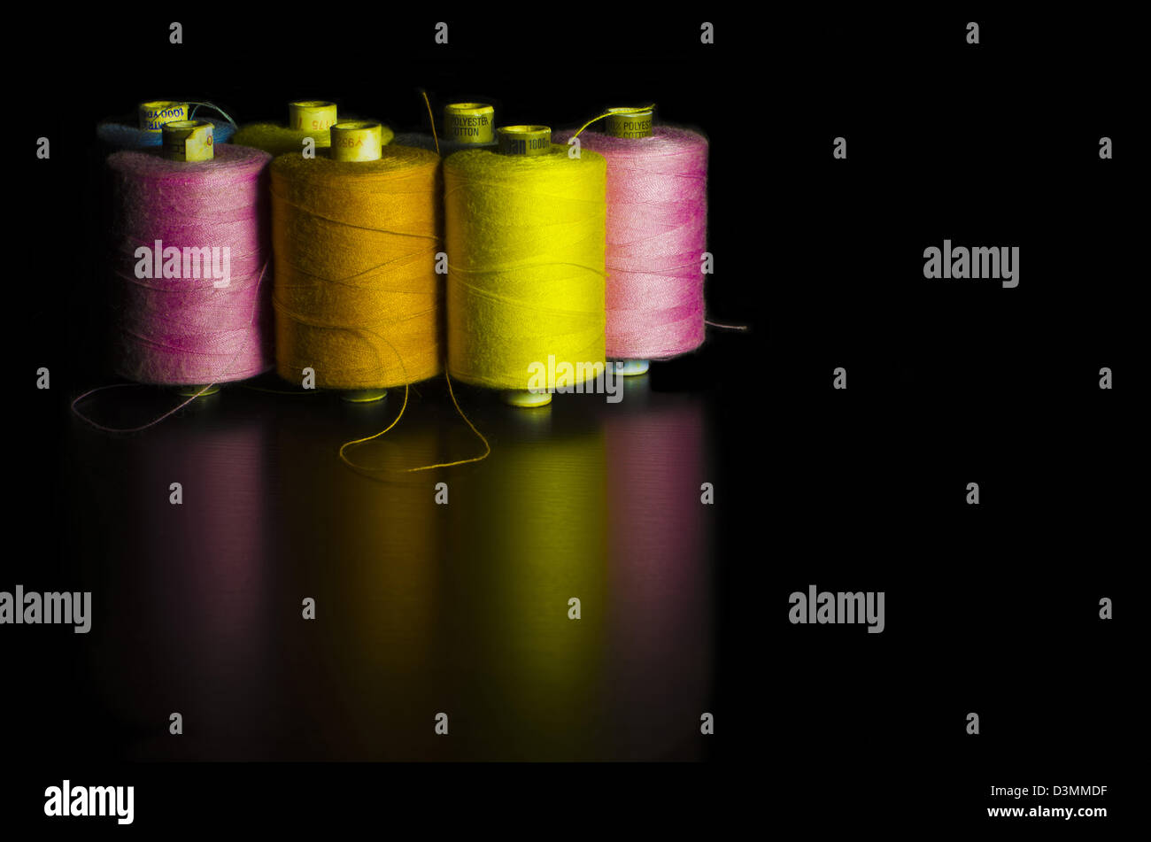 Seven Colorful Cotton Reels against a Black Background Stock Photo