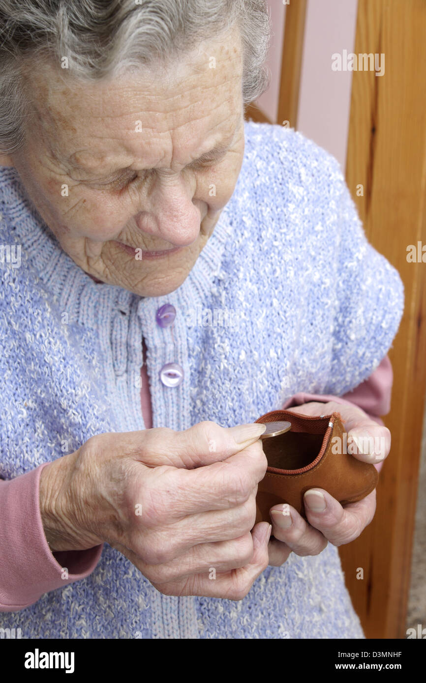 Elderly woman looking in her purse counting the pennys in the age of austerity & troubling times Stock Photo