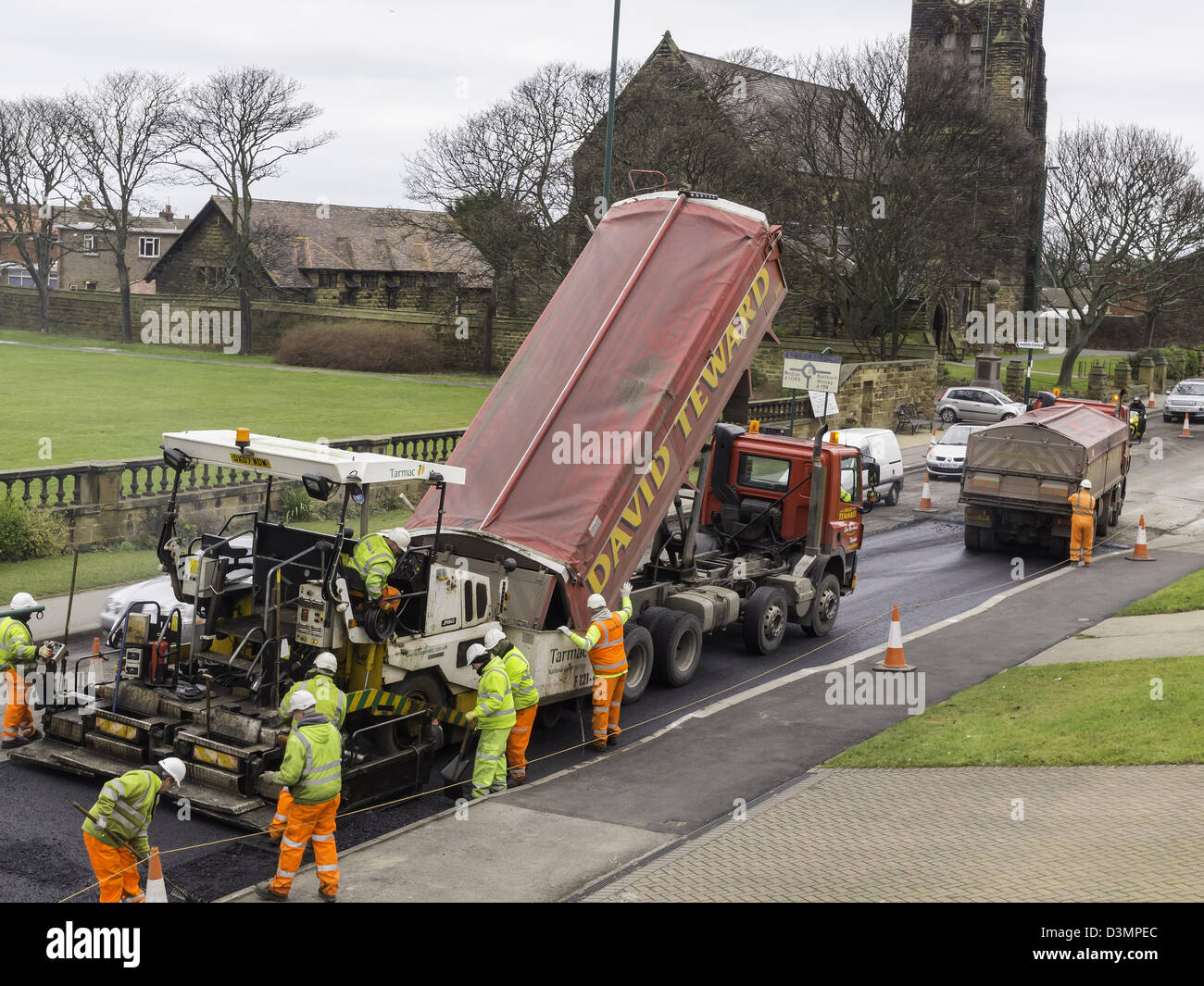 A pavior machine in action laying tarmac base layer on a road resurfacing job Stock Photo
