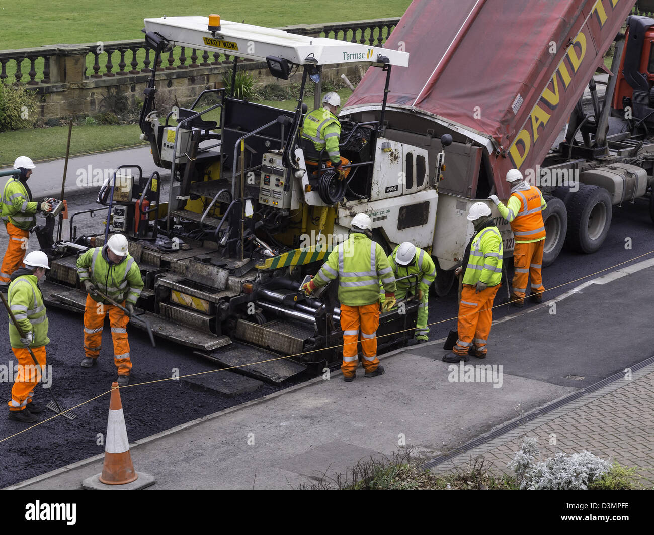 A pavior machine in action laying tarmac base layer on a road resurfacing job Stock Photo