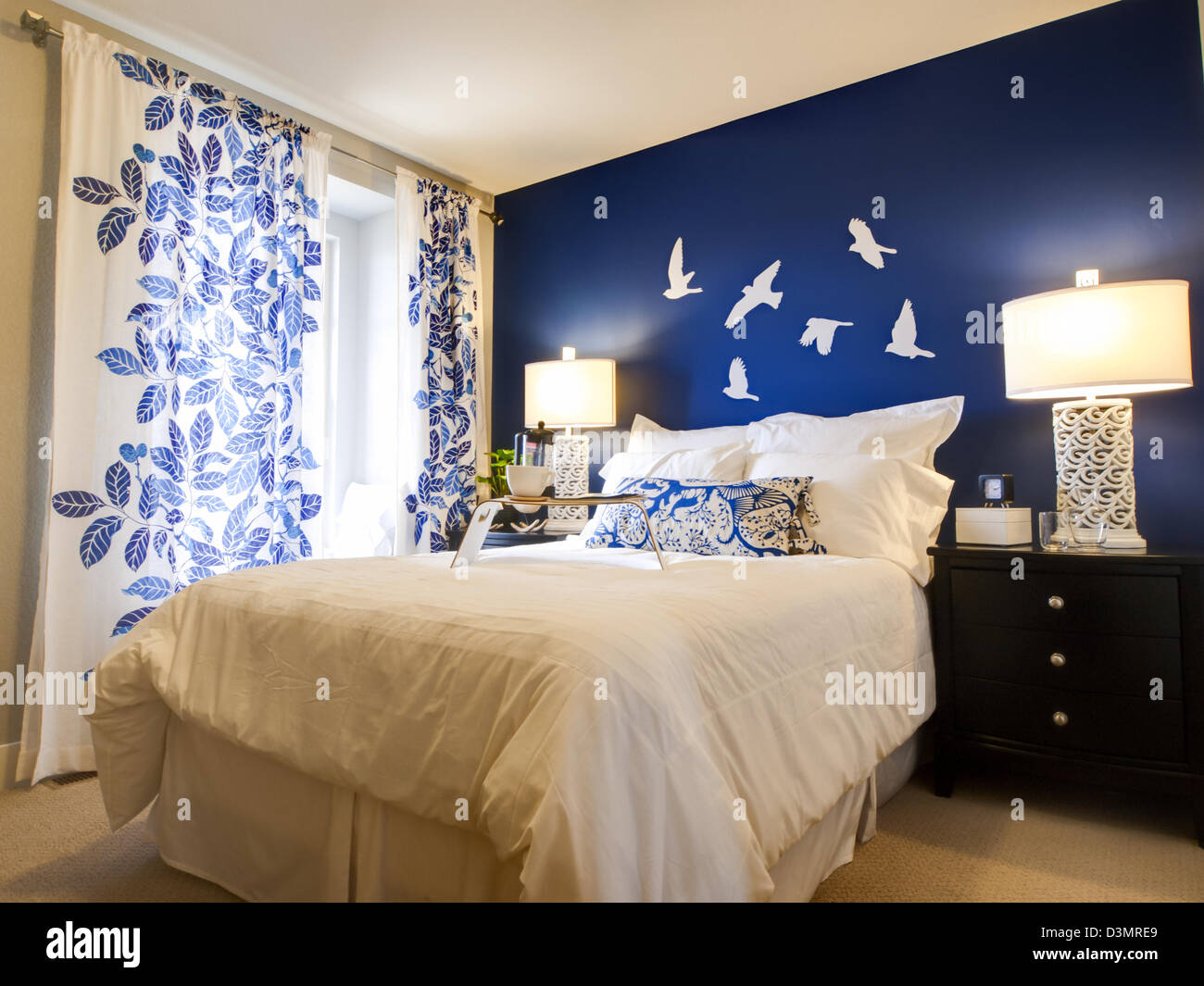 Modern master bedroom with blue wall and white linens Stock Photo - Alamy