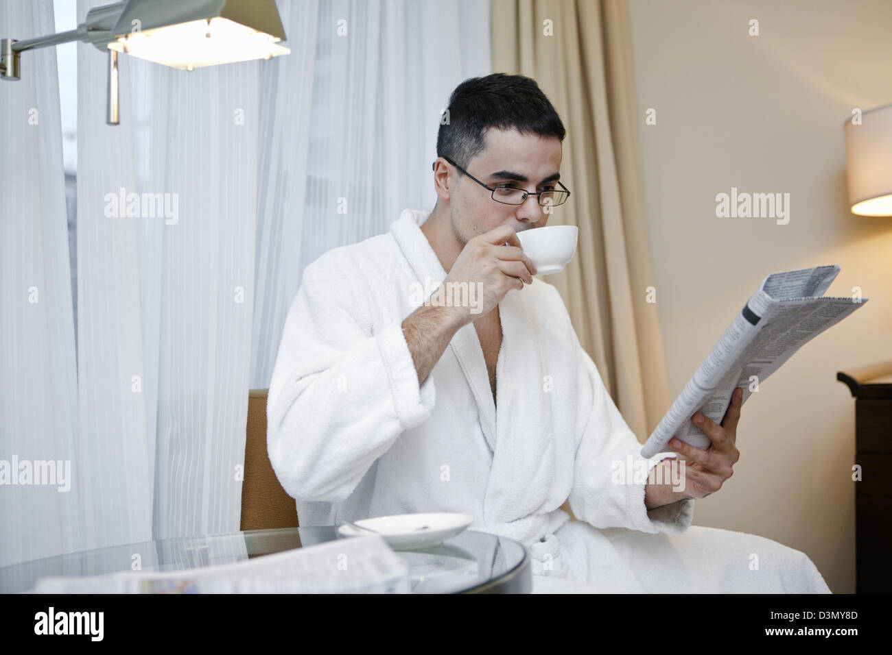 Traveling businessman drinks coffee and reads morning paper in early morning Stock Photo