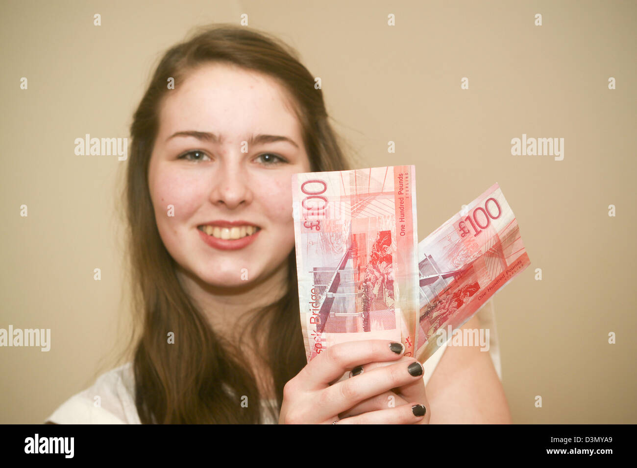 16 year old girl holding two £100 notes Stock Photo