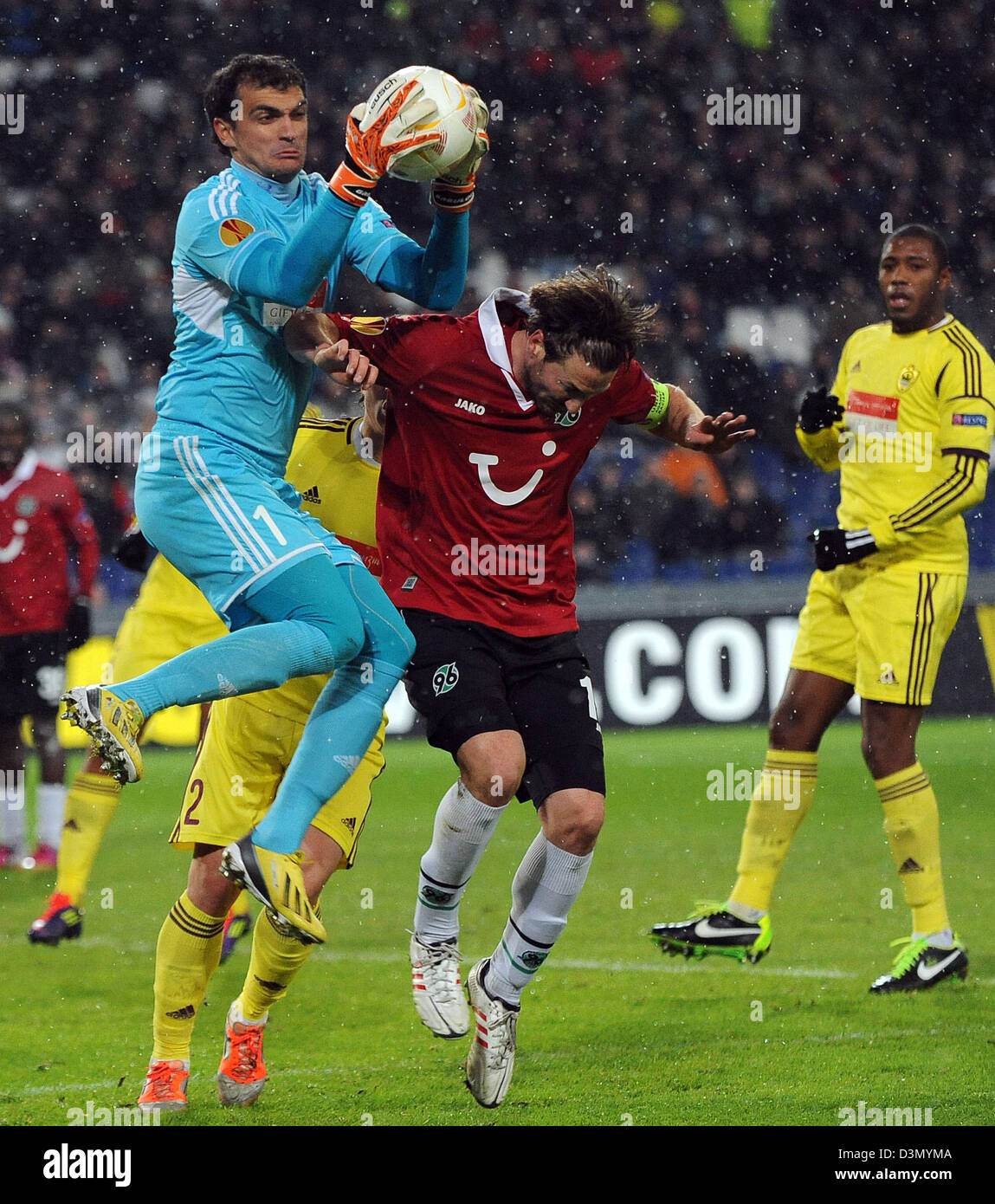 Hanover's Christian Schulz (C) and Makhachkala's goalkeeper Vladimir Gabulov (L) vie for the ball during the UEFA Europa League round of 32 second leg soccer match between Hanover 96 and FC Anzhi Makhachkala at Hannover Arena in Hanover, Germany, 21 February 2013. Photo: Peter Steffen/dpa +++(c) dpa - Bildfunk+++ Stock Photo