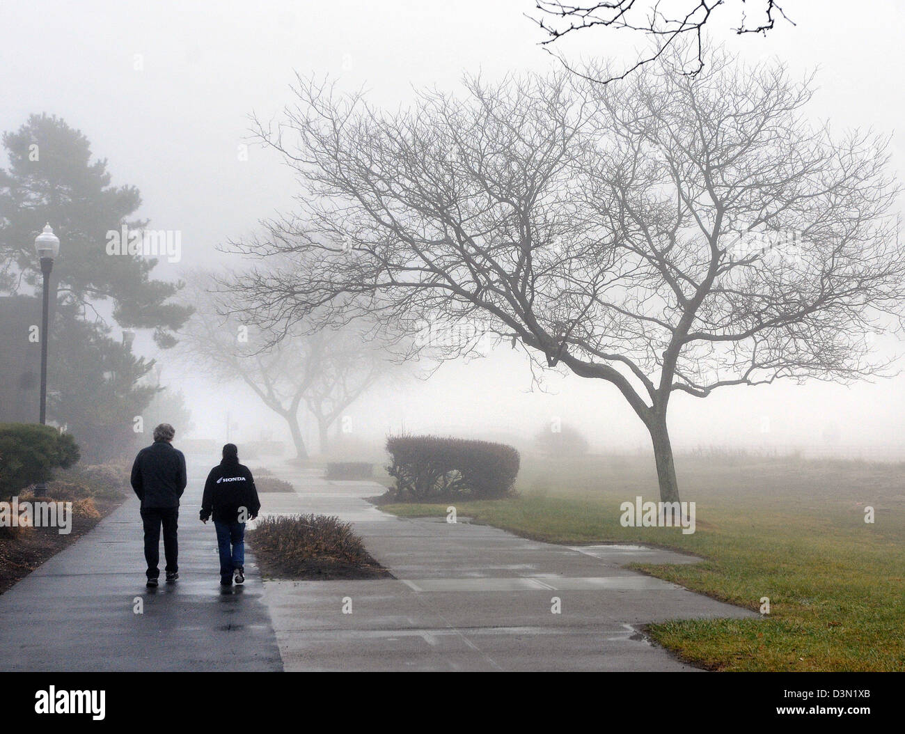 Pdeople walking along a foggy shoreline walkway in CT USA Stock Photo