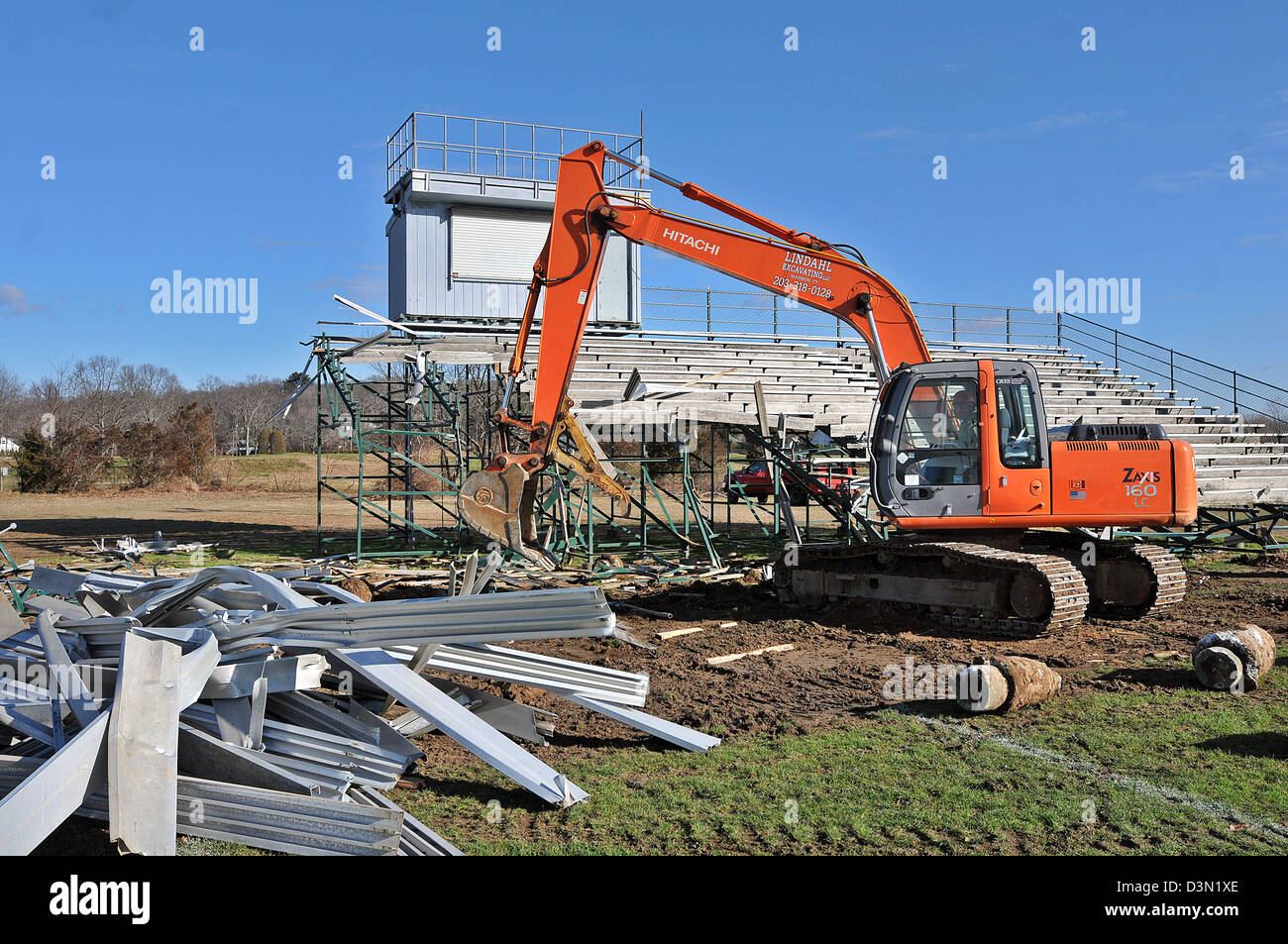 A wrecker tears down the bleachers at a football stadium in Madison CT USA as the town prepares to build a new one. Stock Photo