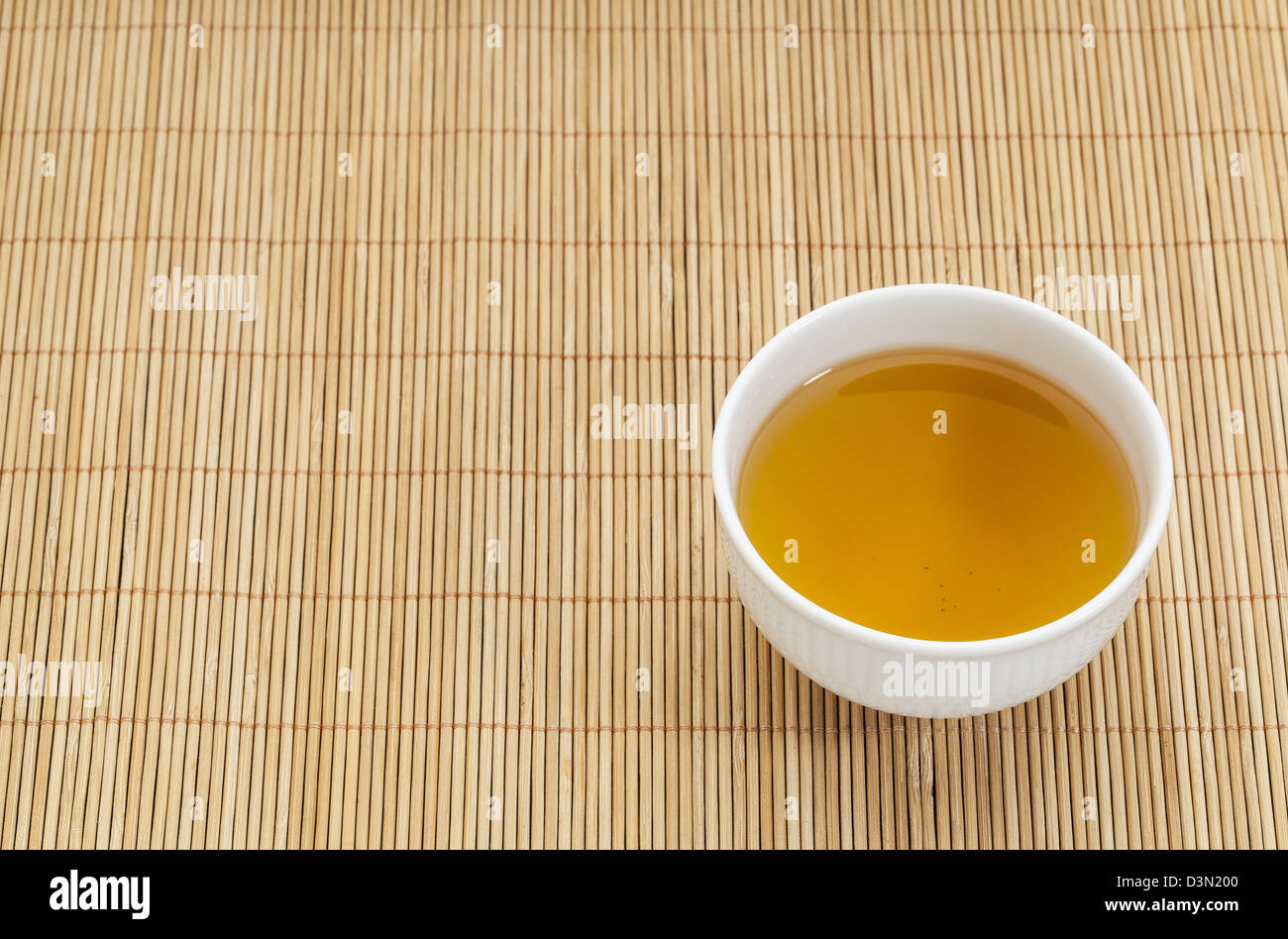 white china cup of green tea against bamboo place mat Stock Photo