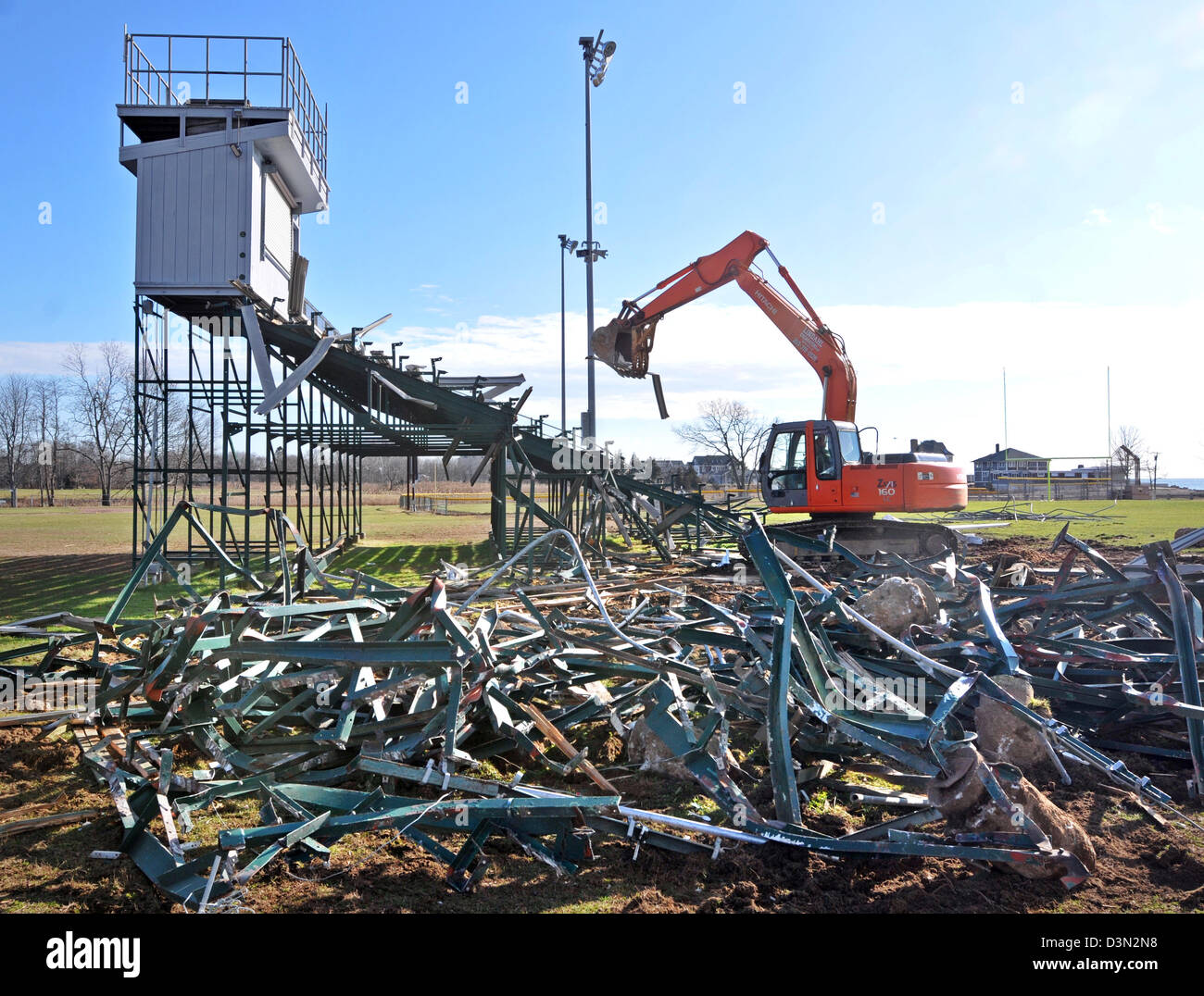 A wrecker tears down the bleachers at a football stadium in Madison CT USA as the town prepares to build a new one. Stock Photo