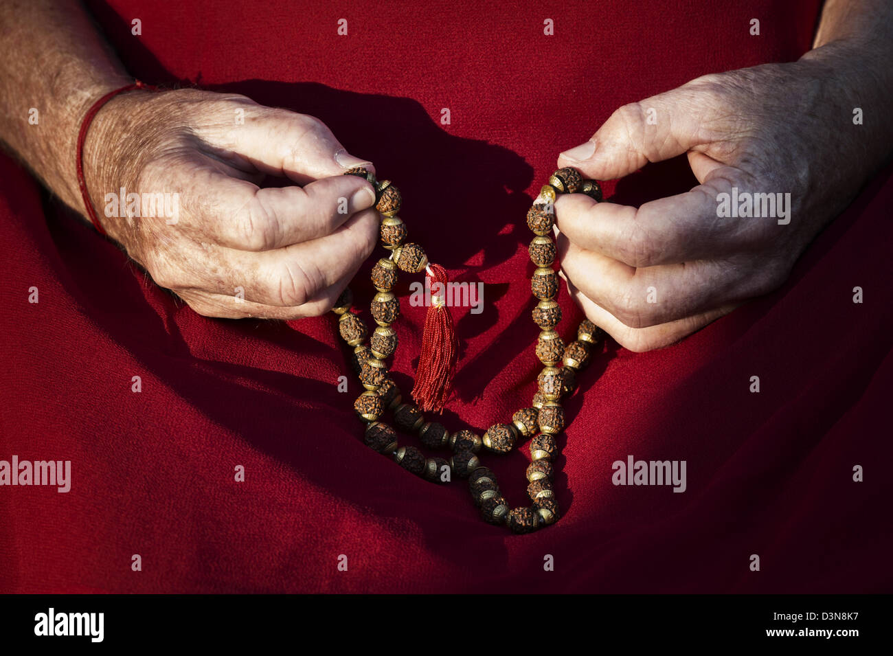 Old mans hands holding Indian Rudraksha / Japa Mala prayer beads Stock Photo