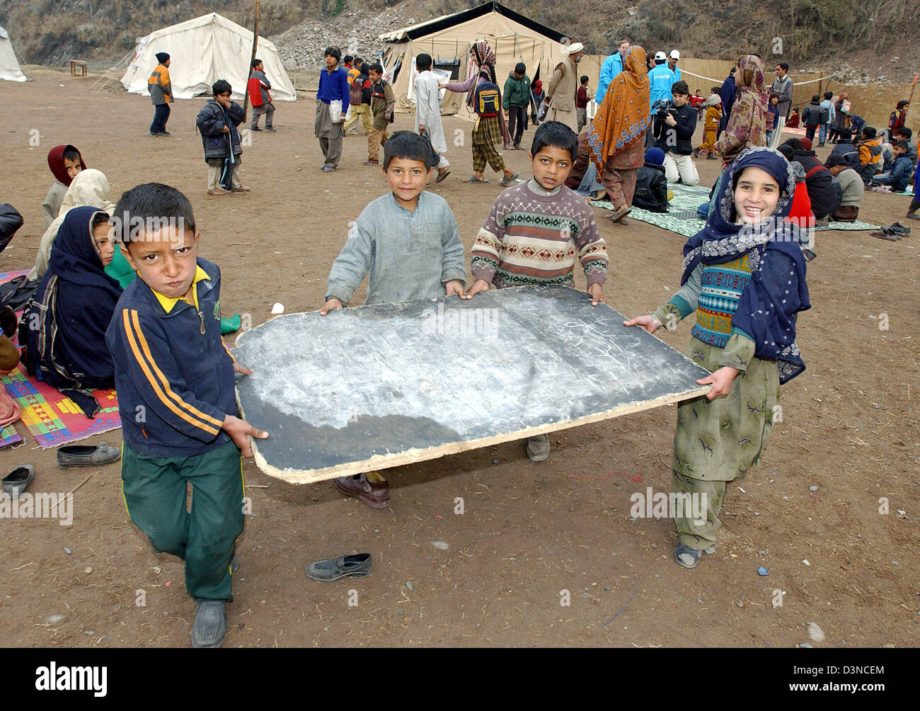 Schoolchildren carry a blackboard to their lesson in a refugee camp  near the town of Muzaffarabad, Pakistan, Tuesday, 31 January 2006. Millions of people suffered in the aftermath of an earthquake which struck in October 2005 hitting the province of Kashmir. Photo: Wolfgang Langenstrassen Stock Photo
