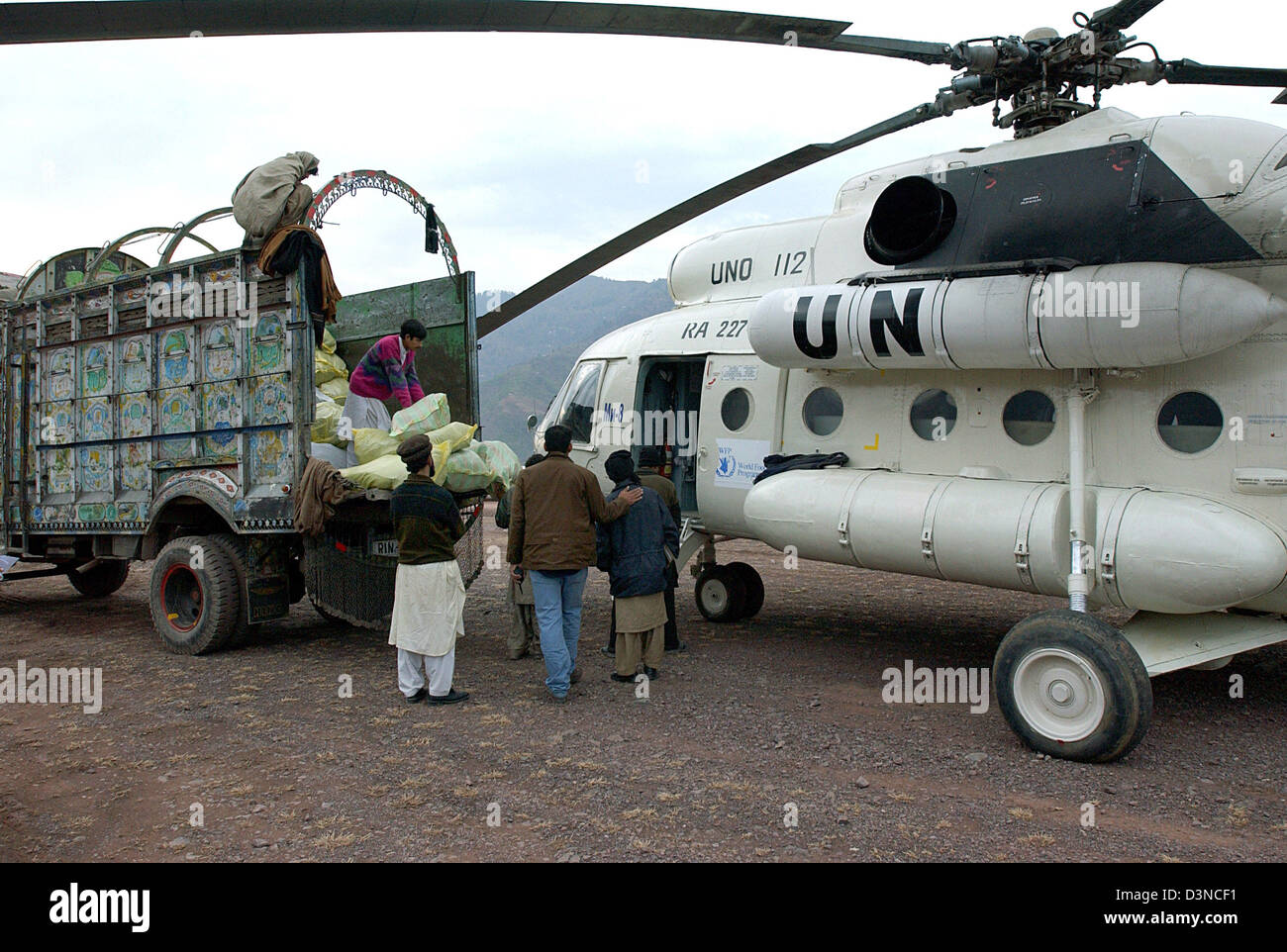 Local mountain dwellers load bags of aid supplies onto a Russian helicopter near  Muzaffarabad in Pakistan, Monday, 30 January 2006. Millions of people suffered in the aftermath of an earthquake which struck in October 2005 hitting the province of Kashmir. Photo: Wolfgang Langenstrassen Stock Photo