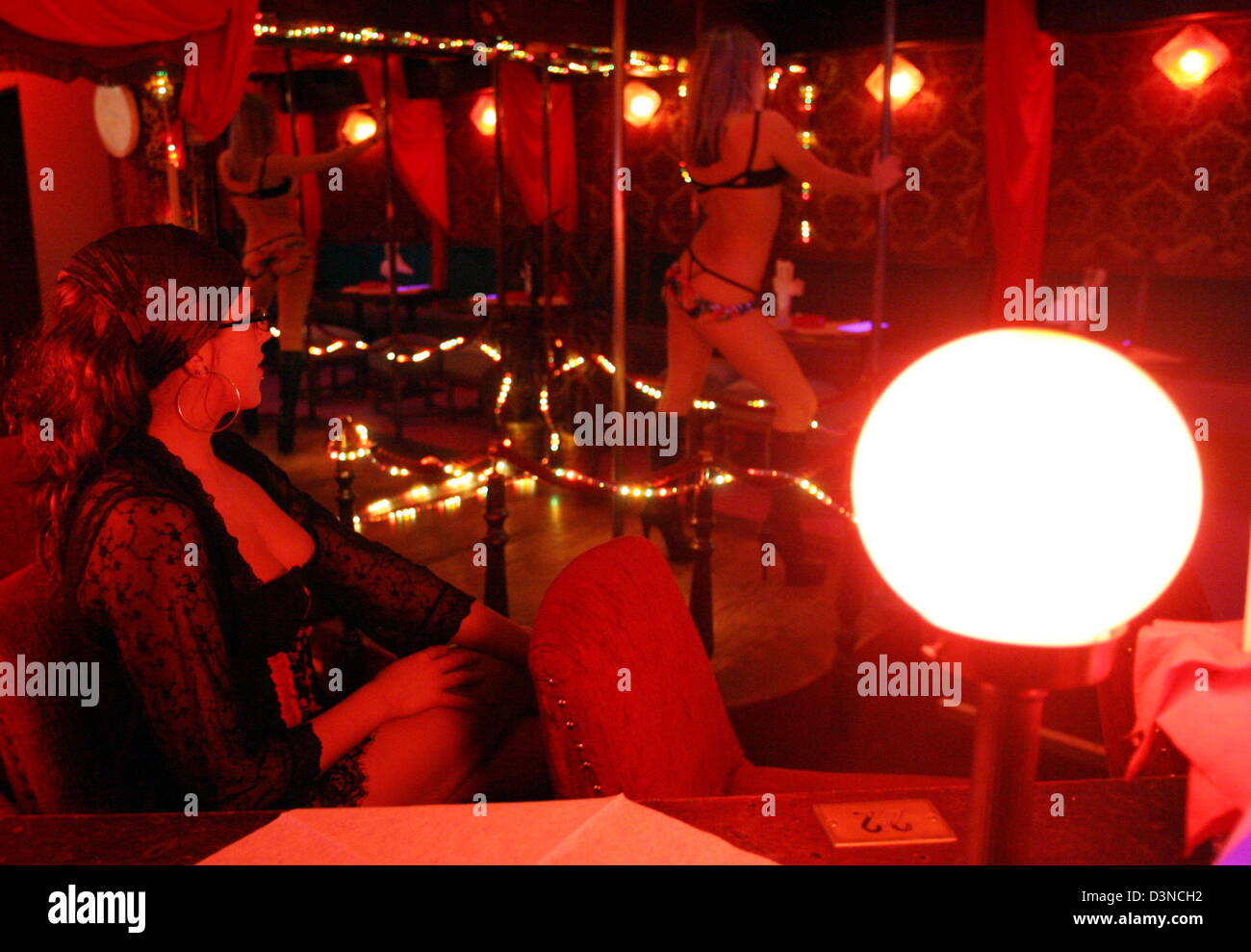 A young woman dances in a red lit tabledance club located on the Reeperbahn amusement street in Hamburg, Germany, Tuesday night, 28 March 2006. The Reeperbahn is considered the longest amusement street in the world. Photo: Kay Nietfeld Stock Photo