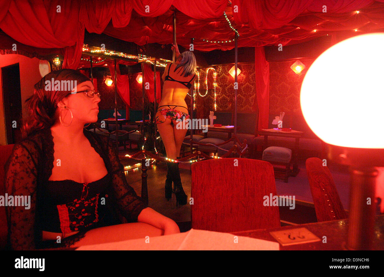 A young woman dances in a red lit tabledance club located on the Reeperbahn amusement street in Hamburg, Germany, Tuesday night, 28 March 2006. The famous Reeperbahn is considered the longest amusement street in the world. Photo: Kay Nietfeld Stock Photo