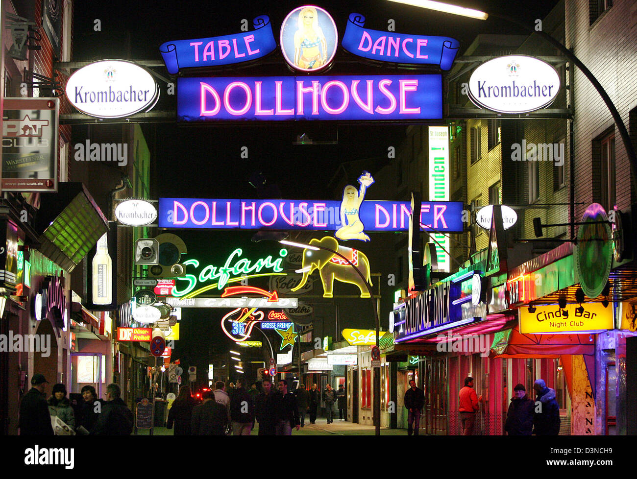 Pedestrians walk underneath colourful neon-lit signs advertising adult entertainment clubs on the famous Reeperbahn amusement street in Hamburg, Germany, Tuesday night, 28 March 2006. The famous Reeperbahn is considered the longest amusement street in the world. Photo: Kay Nietfeld Stock Photo