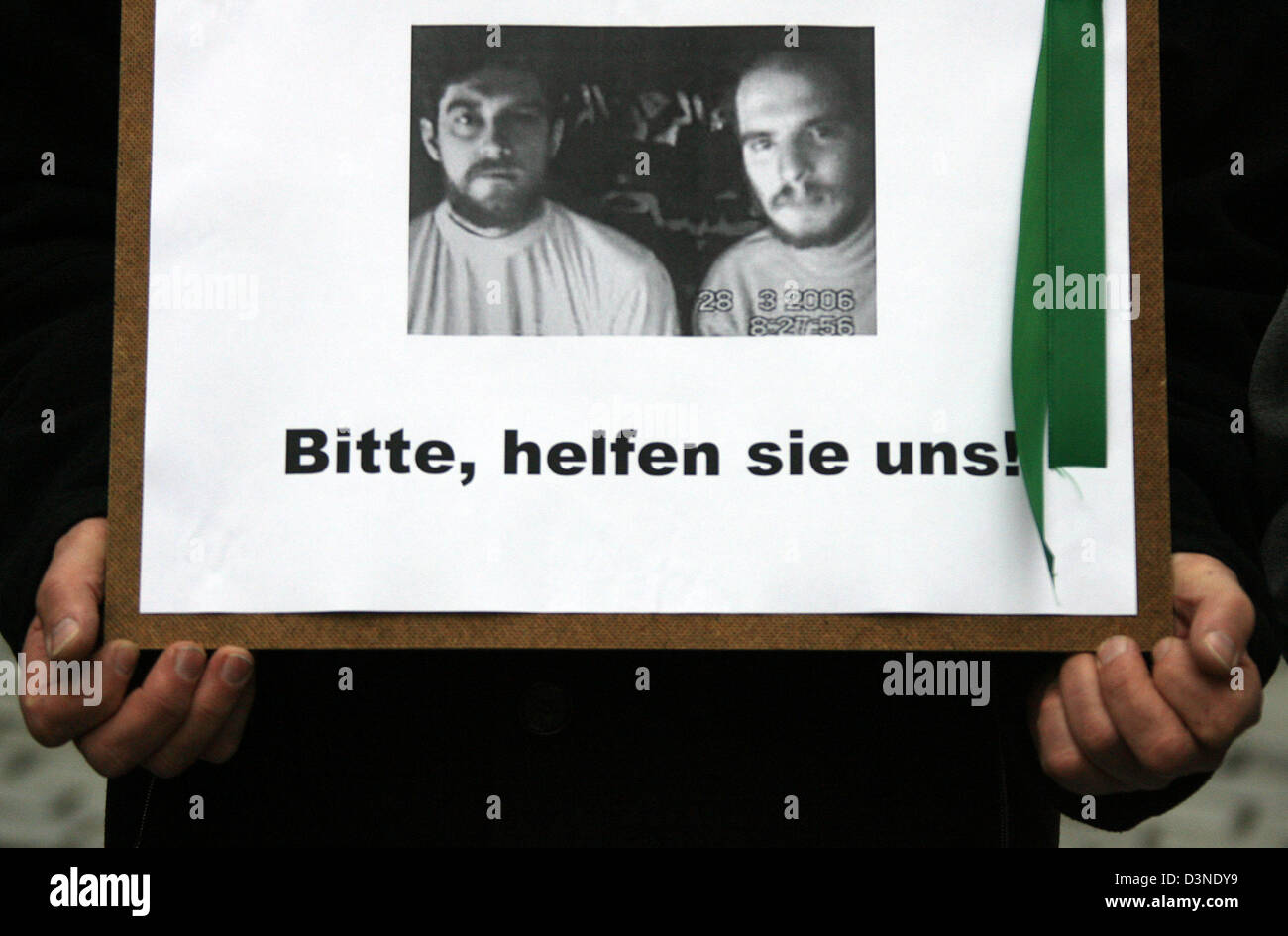 A colleague of the two German engineers kidnapped in Iraq holds a placard reading the hostages' plea 'Bitte, helfen sie uns' (Please help us) at the 22nd solemn vigil in front of the Nikolai Church in Leipzig, Germany, 13 April 2006. Even after the kidnappers' last video message the fate of René Braeunlich and Thomas Nitzschke remains unclear. Photo: Peter Endig Stock Photo