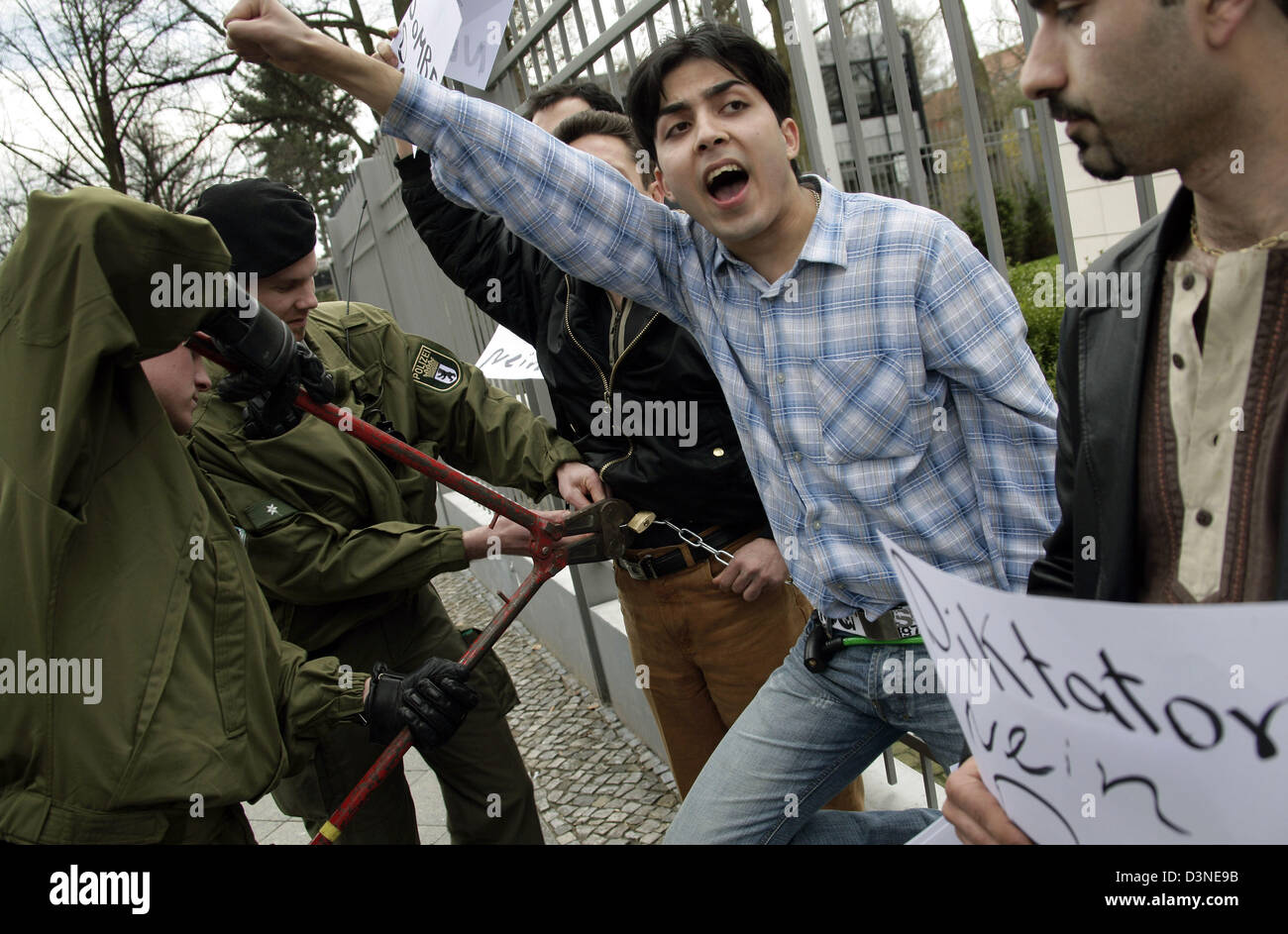 Exile-Iranians chain themselves to a fence in front of the Iranian embassy to demonstrate against their home country's nuclear policy, while policemen uncertain them, Berlin, Germany, Tuesday 18 April 2006. The protesters are against a possible nuclear armament of Iran. Photo: Peer Grimm Stock Photo