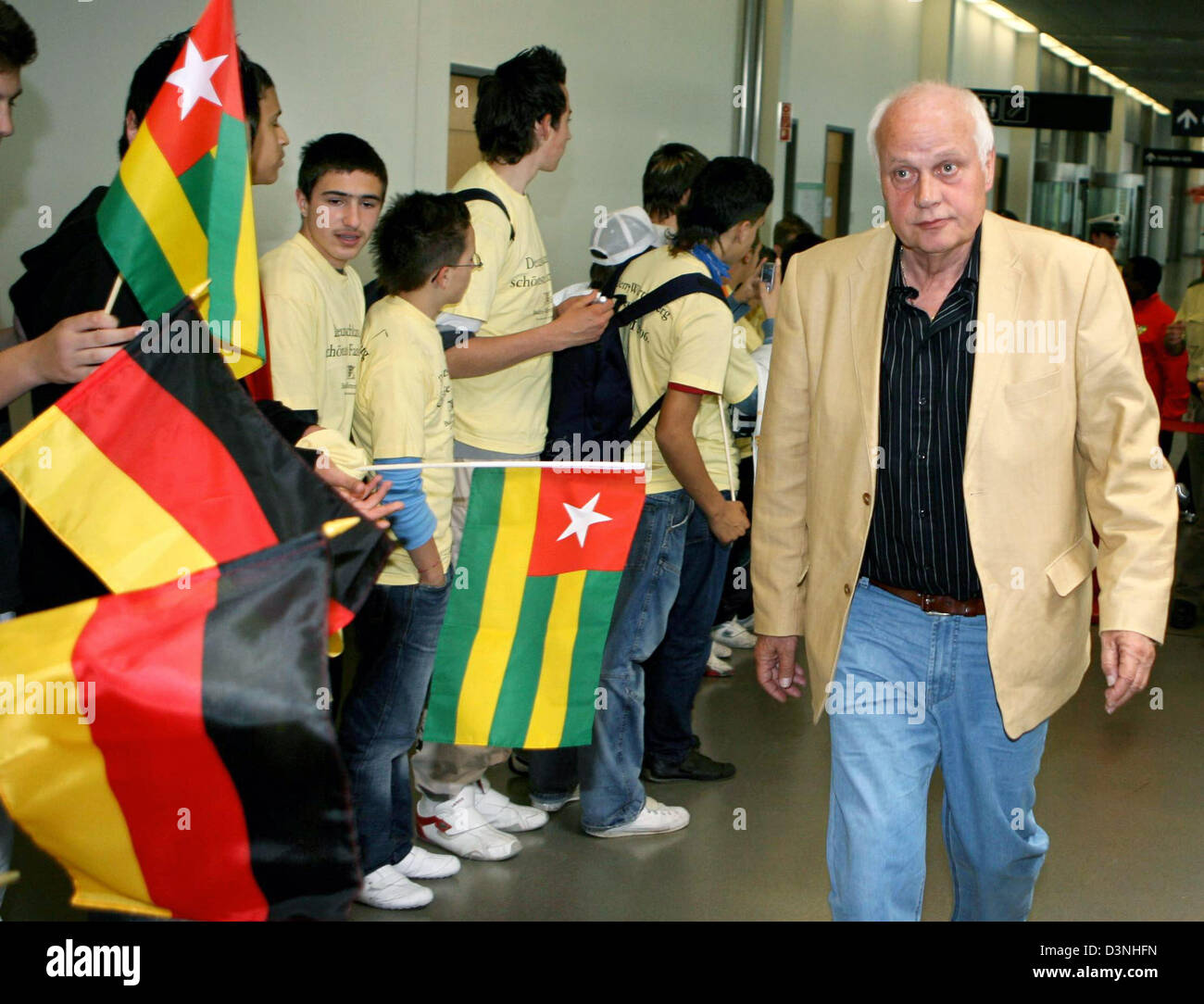 Otto Pfister, German head coach of Togo national soccer team, passes teenagers with the Togo flag after the team's arrival at the airport of Stuttgart, Germany, Monday, 15 May 2006. The Togo national team is the first FIFA WOrld Cup 2006 team to move into its accomodation in Wangen. Photo: Bernd Weissbrod Stock Photo