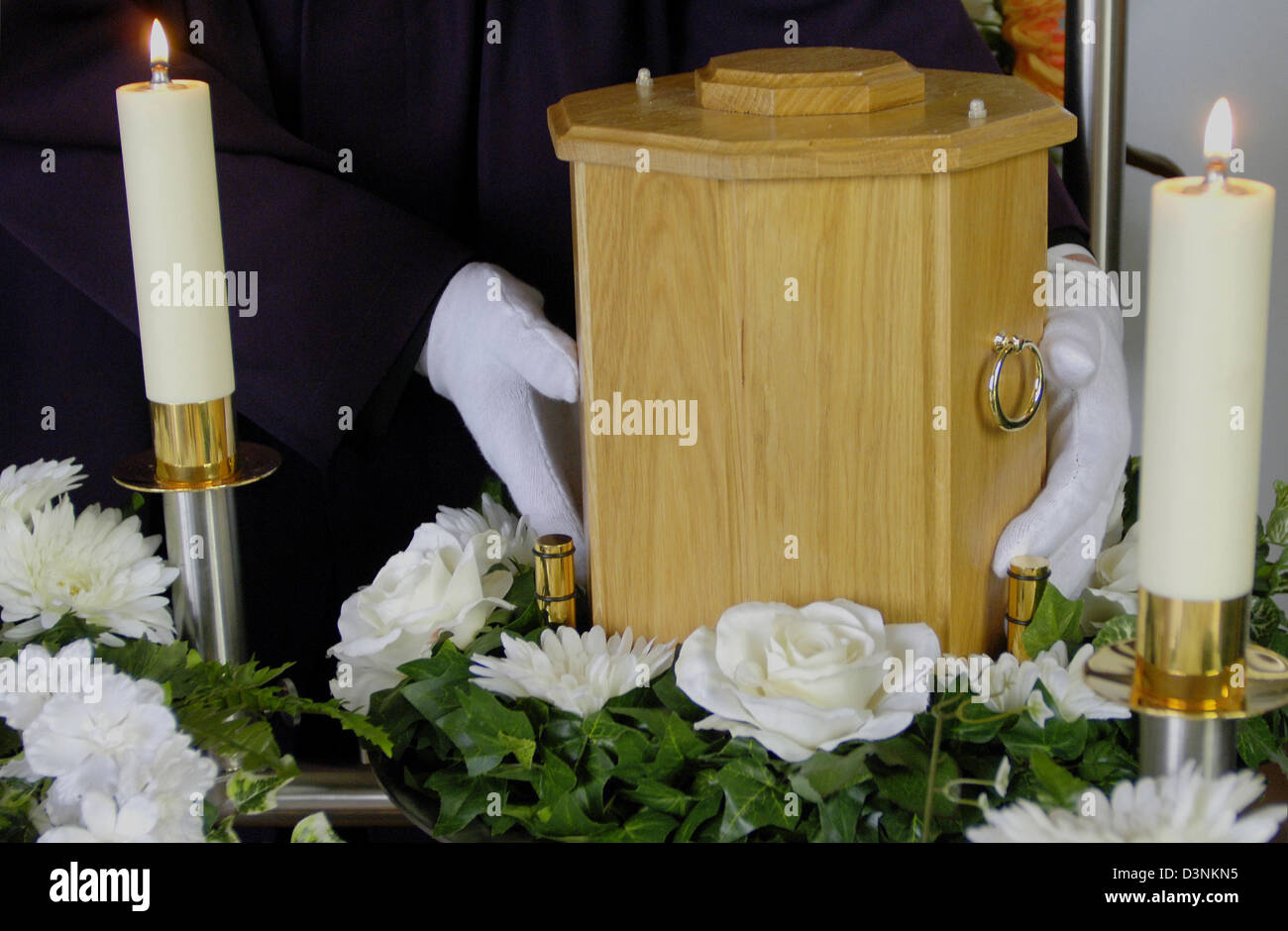 A pallbearer of funeral undertaker Karl Schumacher places an urn in a