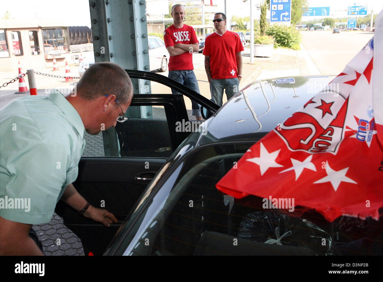 A German border control officer checks the car of Swiss soccer fans at the German-Swiss border control station Basel-Weil am Rhein, Germany, Tuesday, 13 June 2006. Police and border control intesified the controls at the borders of Switzerland and France due to the FIFA World Cup Group G match France vs Switzerland today in Stuttgart, Germany. Photo: Rolf Haid Stock Photo