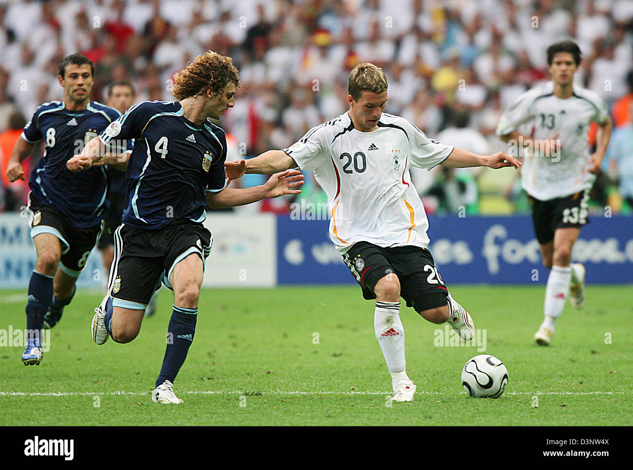 German national soccer player Lukas Podoalski (2nd R) shoots the ball, while Fabricio Coloccini (2nd L), Javier Mascherano (L) of Argentina and Michael Ballack (R) of Germany watch the scene during the World Cup quarter final against Argentina at the Olympic Stadium in Berlin, Friday, 30 June 2006. Germany won the quarter final 5:3 on penalties. Photo: Michael Hanschke +++ Mobile S Stock Photo