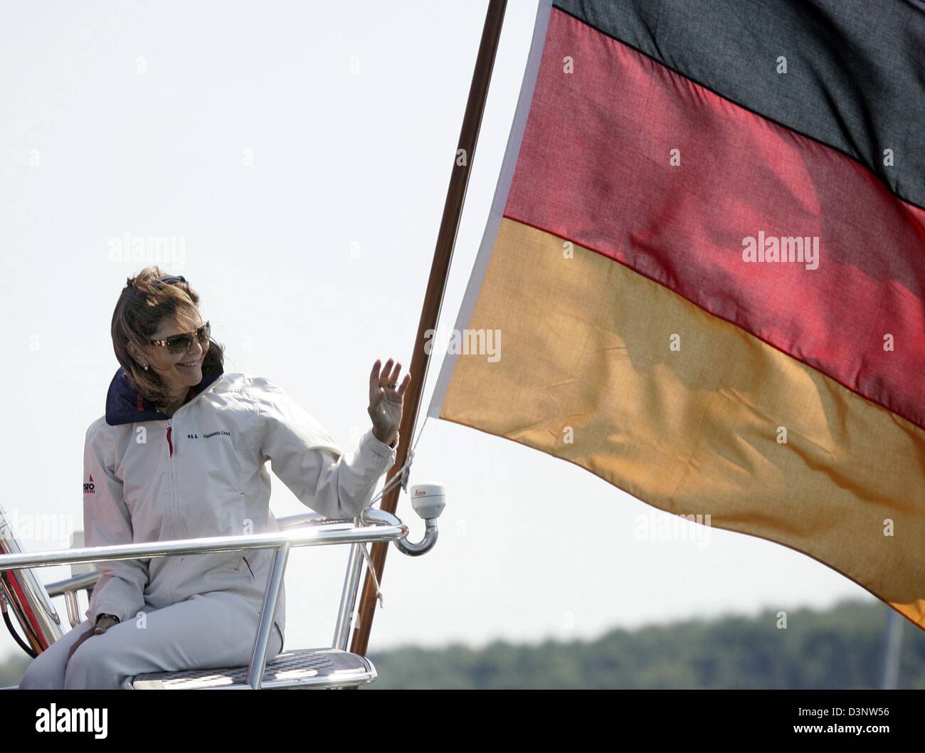 Queen Silvia of Sweden sits and waves on the yacht 'Marantha' next to a German flag in Strande near Kiel, Germany, Monday, 3 July 2006. The monarch with German origin gave the start signal for the 'Childhood Charity Race' at the 'Kieler Förde'. The proceeds will be donated to the 'Childhood Foundation' which Silvia founded. It helps impoverished children all over the world. Photo:  Stock Photo