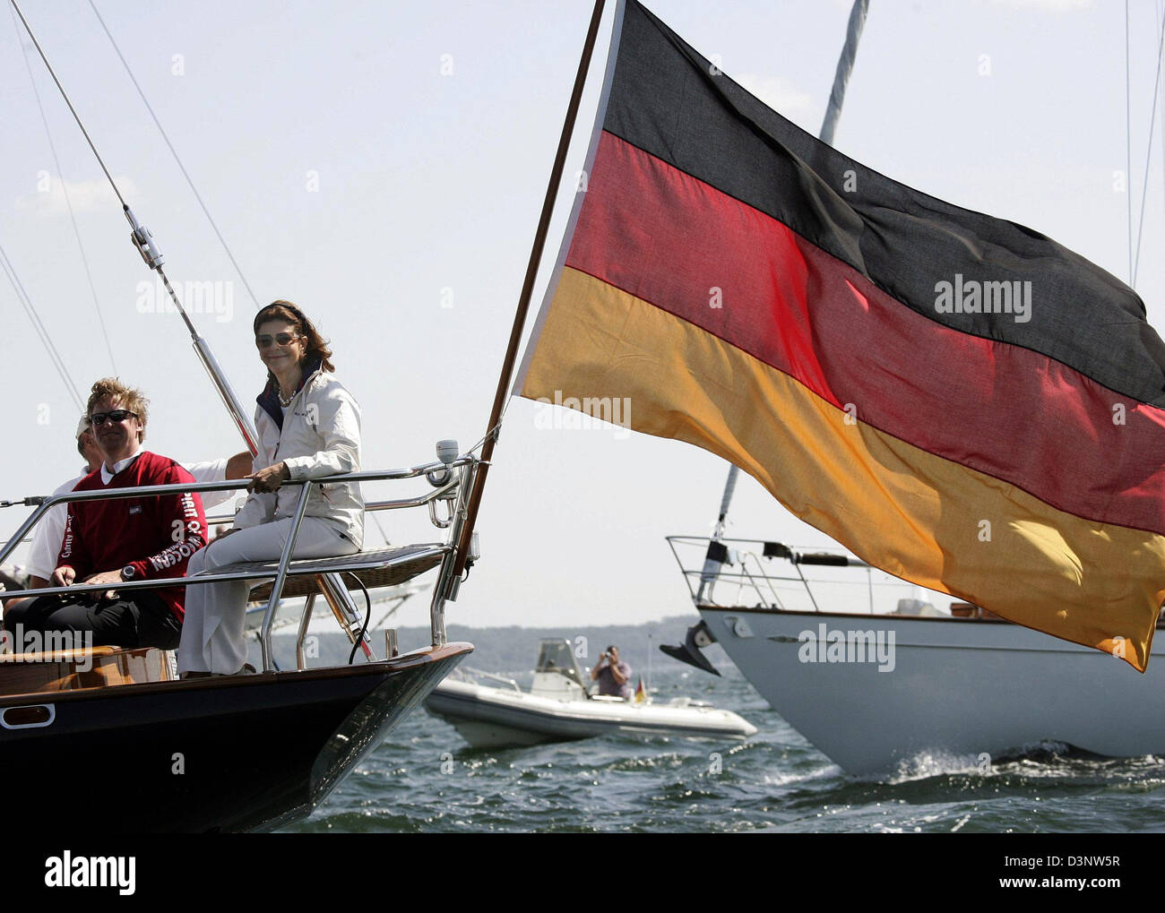 Queen Silvia of Sweden sits next to Alexander Prince of Schleswig-Holstein and a German Flag on the yacht 'Marantha' in Strande near Kiel, Germany, Monday, 3 July 2006. The monarch with German origin gave the start signal for the 'Childhood Charity Race' at the 'Kieler Foerde'. The proceeds will be donated to the 'Childhood Foundation' which Silvia founded. It helps impoverished ch Stock Photo
