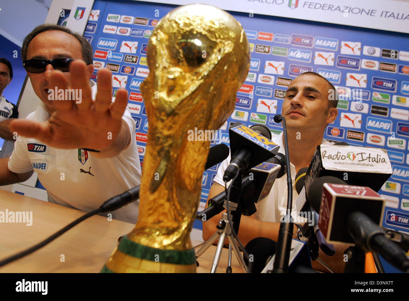 Italian player Fabio Cannavaro (R) sits behind the World Cup trophy during a press conference in Duisburg, Germany, Monday, 10 July 2006. Italy became the new FIFA World Champion defeating France in a penalty shoot-out in Berlin on Sunday. Man at left is unidentified. Foto: Bernd Thissen dpa/lnw +++(c) dpa - Bildfunk+++ Stock Photo