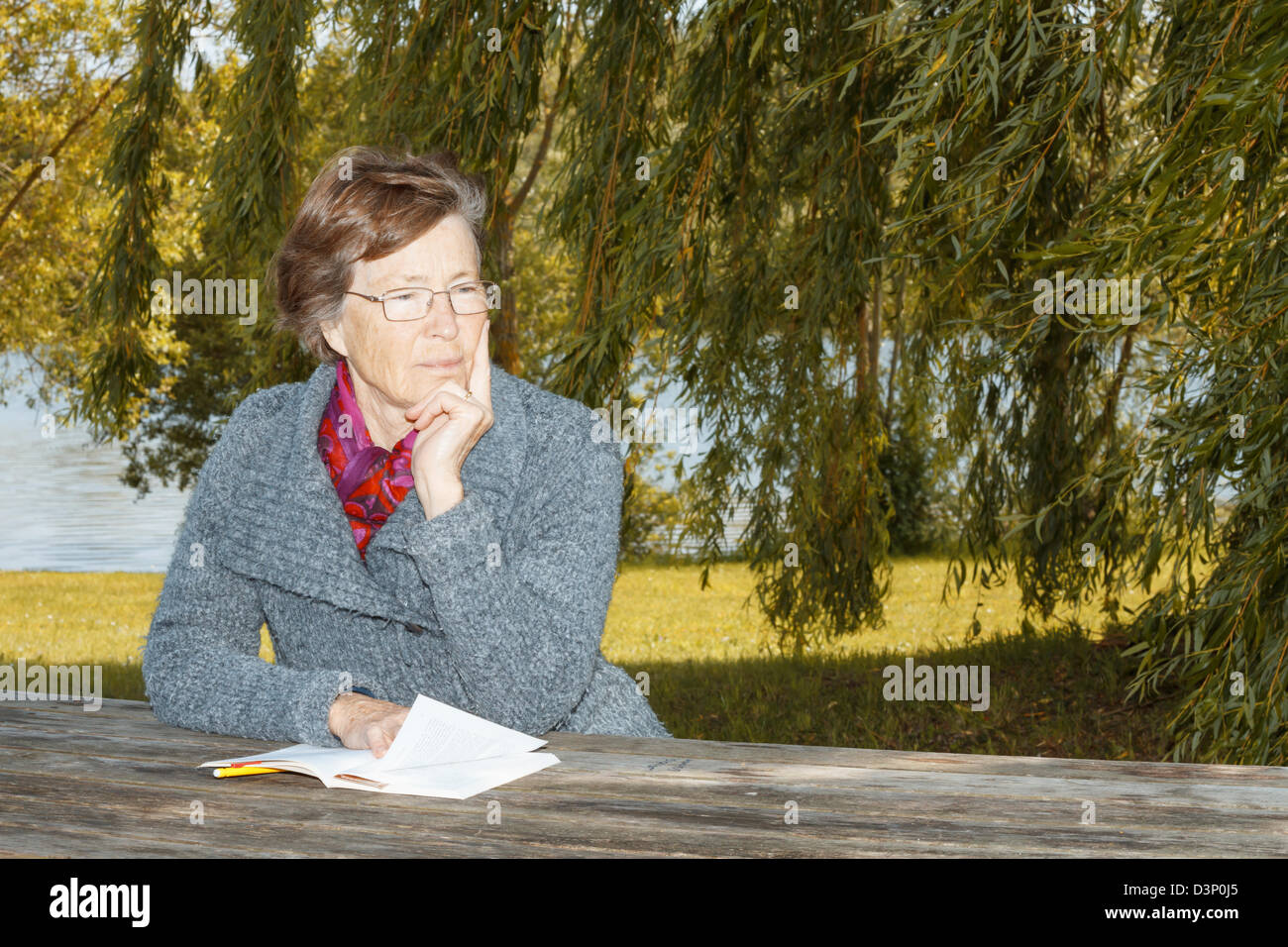 Senior woman sitting at outdoor table. Stock Photo