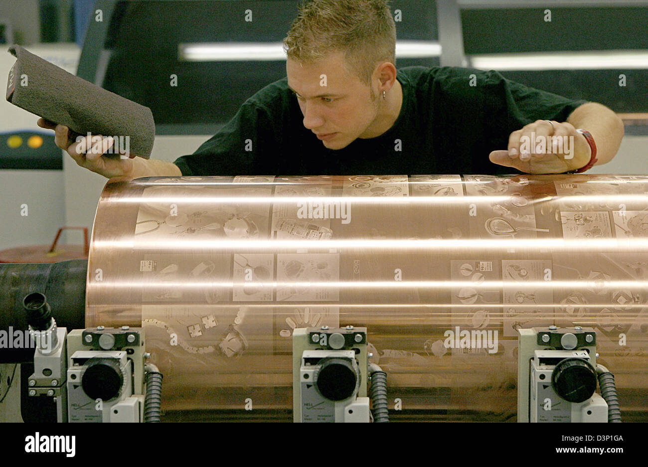 An employee at the print factory Prinovis checks the copper-plated gravure cylinder for possible flaws in Nuremberg, Germany, Tuesday 27 June 2006. Photo: Daniel Karmann Stock Photo