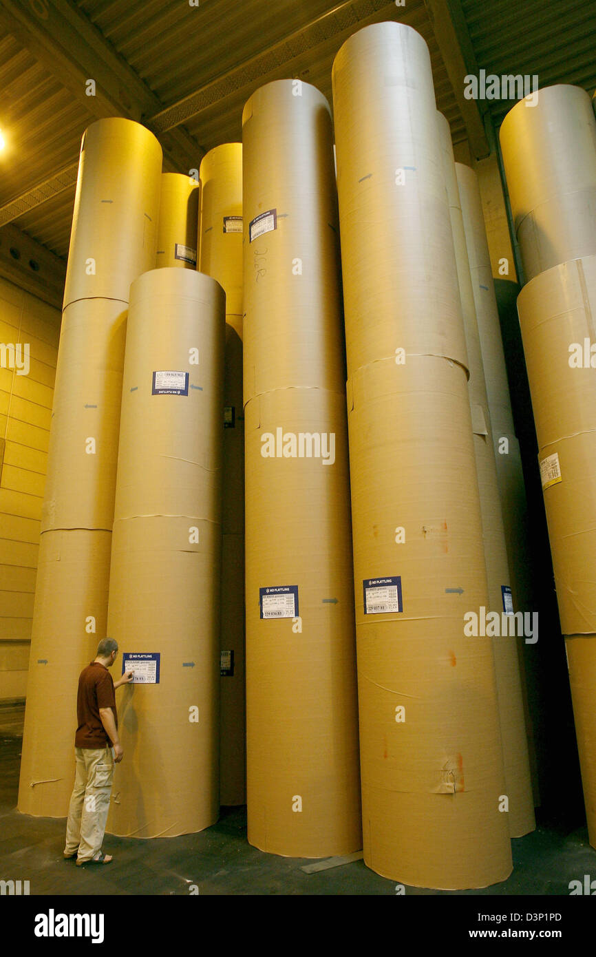 An employee checks stored paper rolls stacked up high in the Prinovis printing plant in Nuremberg, Germany, 27 June 2006. Prinovis is a joint-venture of publishing companies Bertelsmann, Gruner&Jahr and Springer and one of Europe's biggest rotogravure printing companies. Photo: Daniel Karmann Stock Photo
