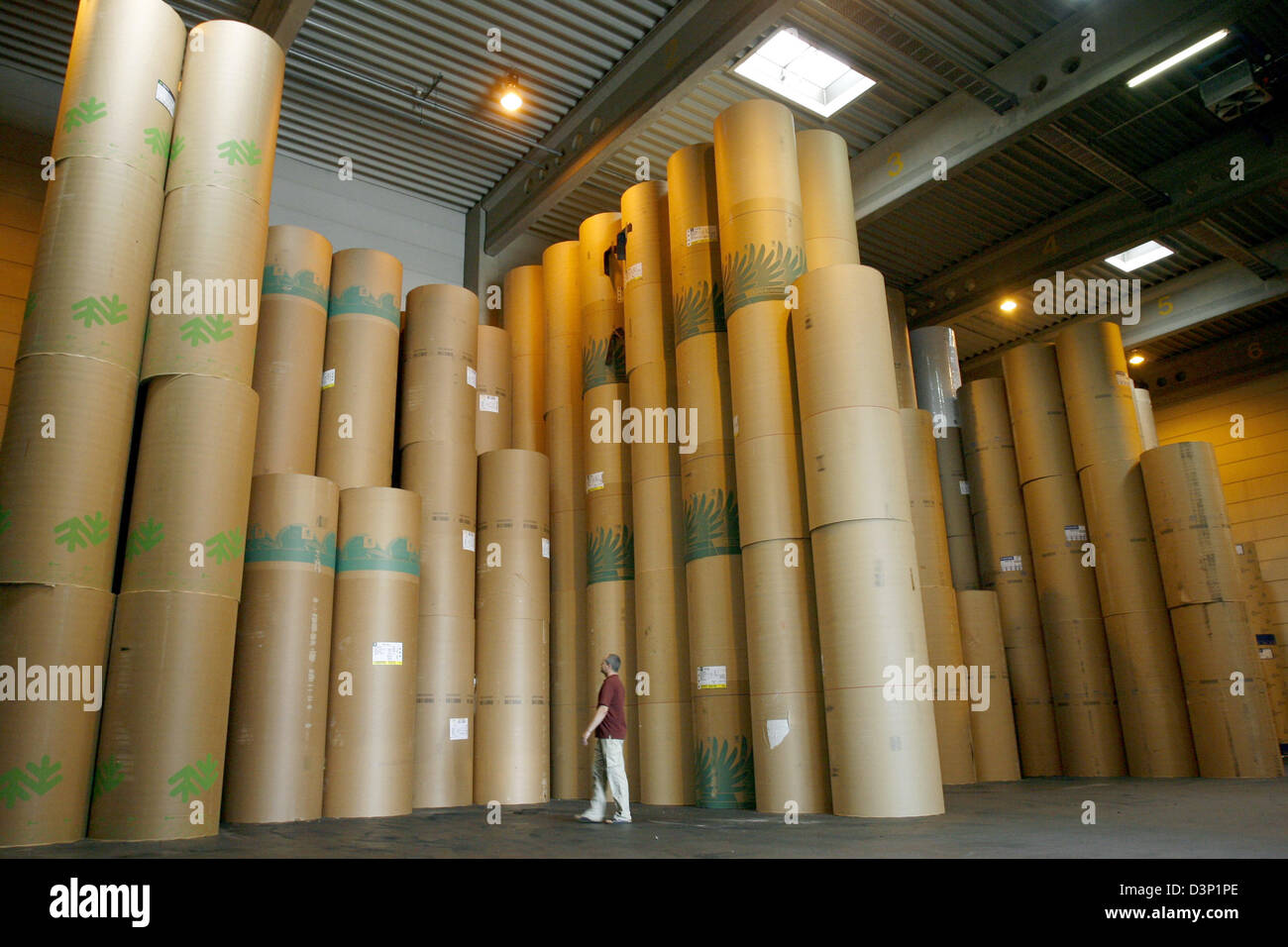An employee checks stored paper rolls stacked up high in the Prinovis printing plant in Nuremberg, Germany, 27 June 2006. Prinovis is a joint-venture of publishing companies Bertelsmann, Gruner&Jahr and Springer and one of Europe's biggest rotogravure printing companies. Photo: Daniel Karmann Stock Photo