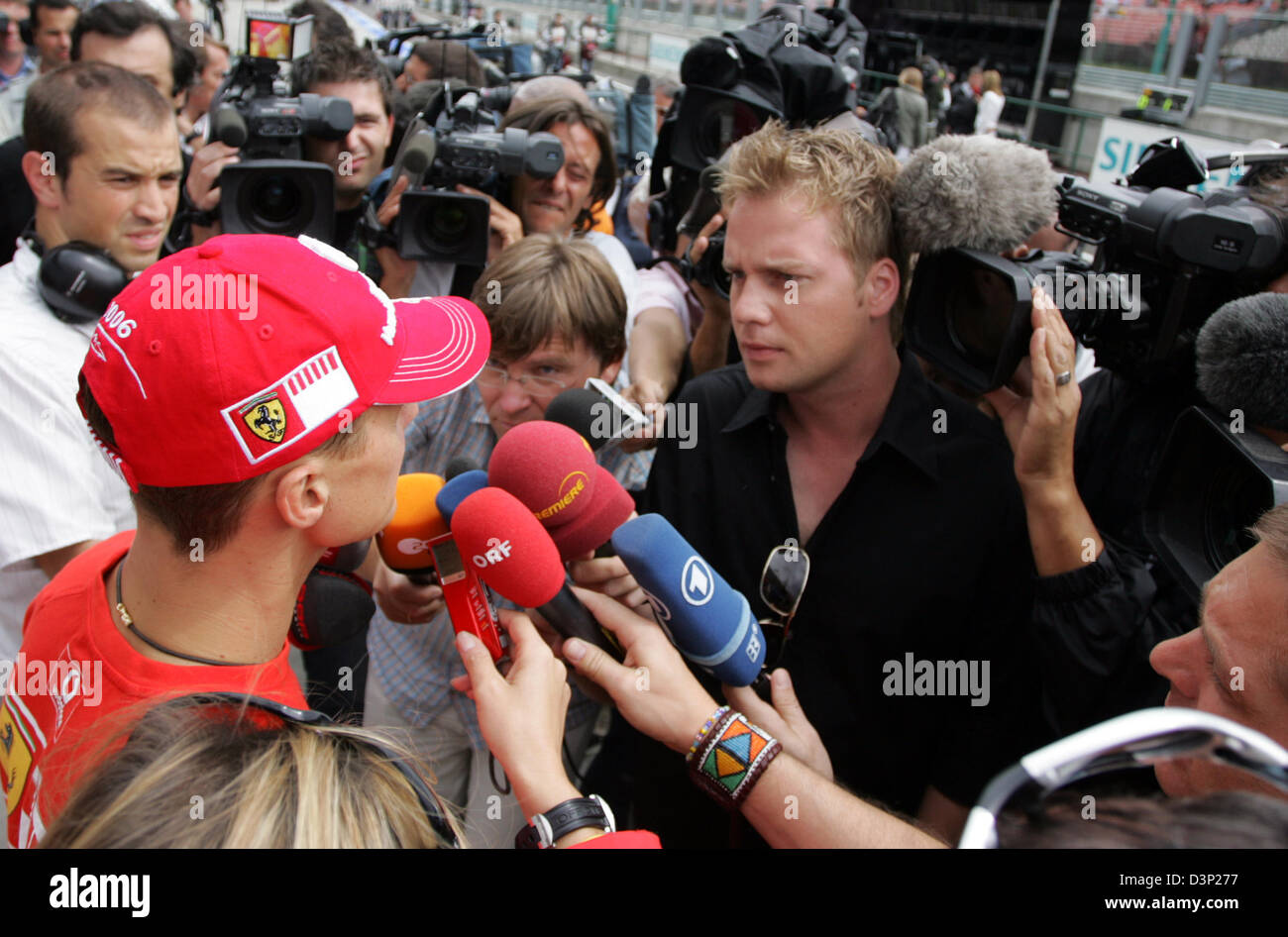 German Formula One driver Michael Schumacher (L) of team Scuderia Ferrari answers journalists' questions after the third practice session of the 2006 Hungarian Grand Prix at the Hungaroring racetrack near Budapest, Hungary, Saturday, 05 August 2006. Schumacher was docked two seconds for overtaking two cars under red flags during Saturday's final practice and lost thereby the pole p Stock Photo