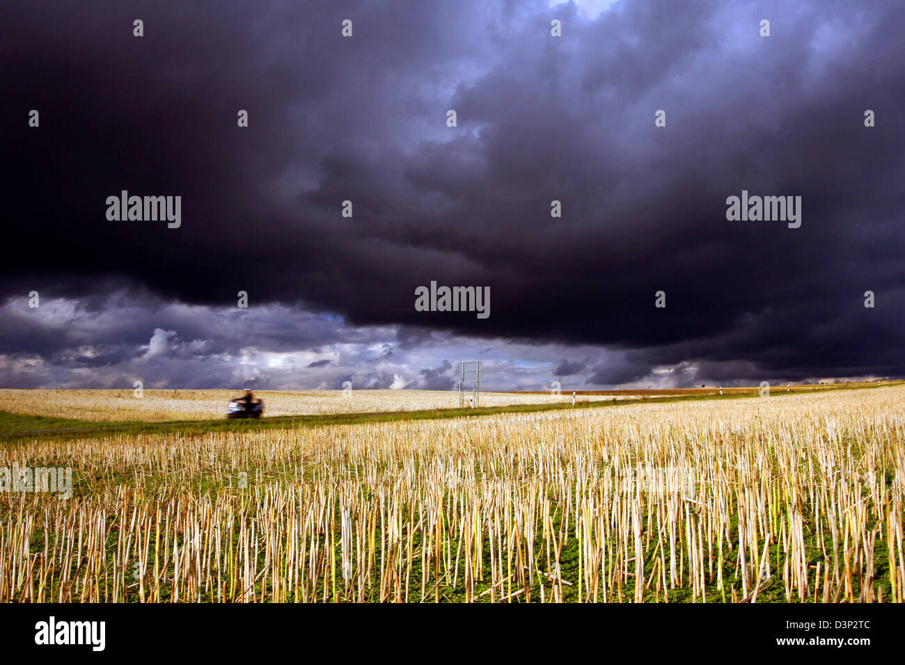 A scooterist passes a hay field under dark clouds near Hettstadt, Germany, Friday, 11 Augusrt 2006. Rain and cool temperatures around 17 degrees Celsius reign in the coming days. Photo: Karl-Josef Hildenbrand Stock Photo