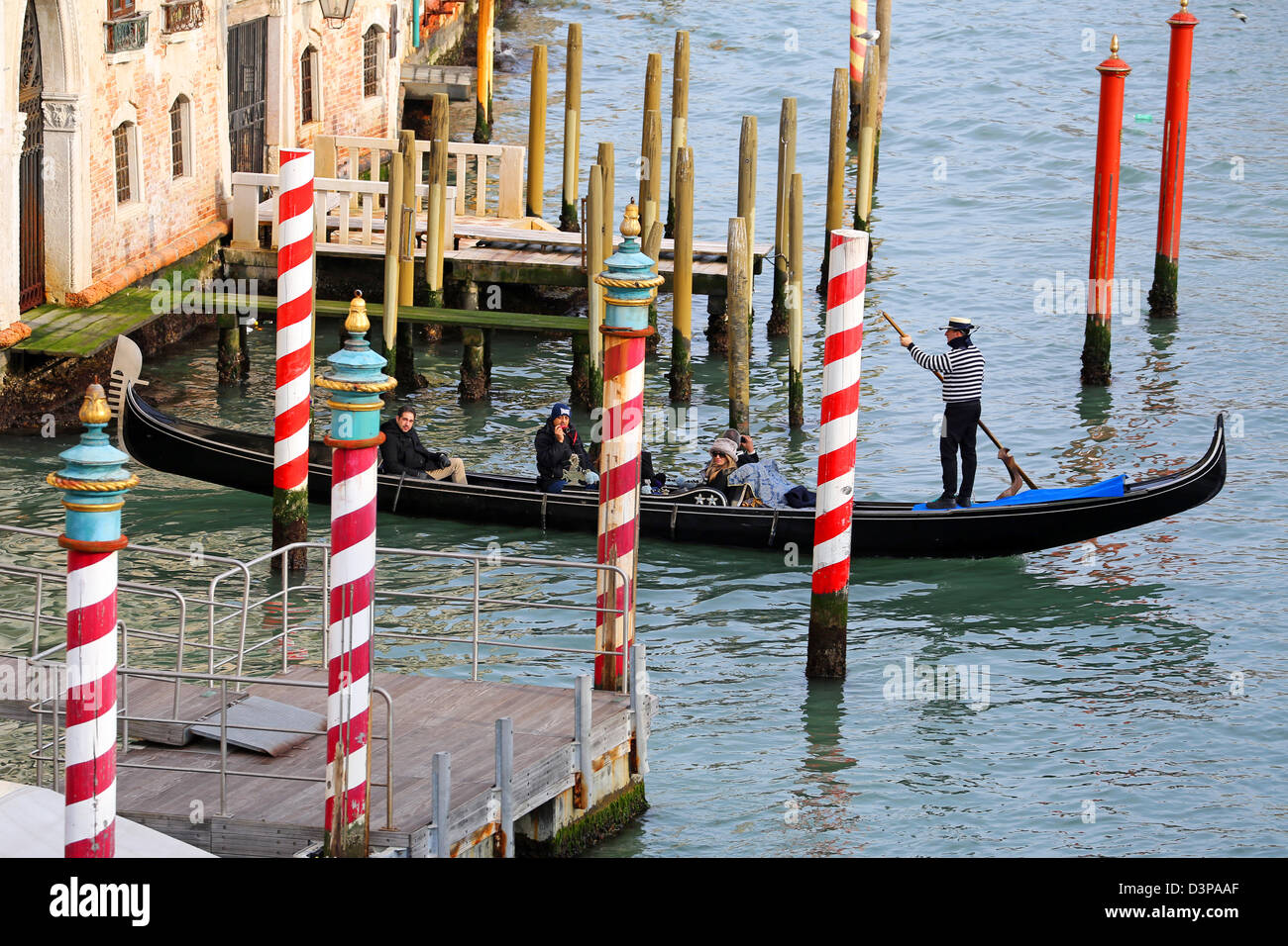 Gondola and Red and white striped gondola mooring posts on the Grand Canal, in Venice, Italy Stock Photo