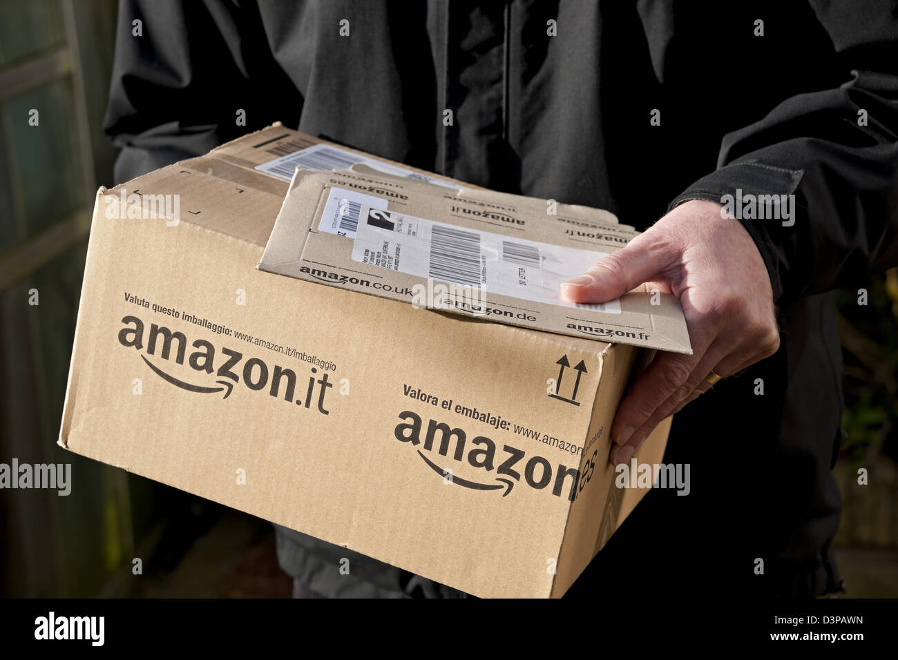 Close up of person man carrying holding Amazon packages package box parcel delivery England UK United Kingdom GB Great Britain Stock Photo